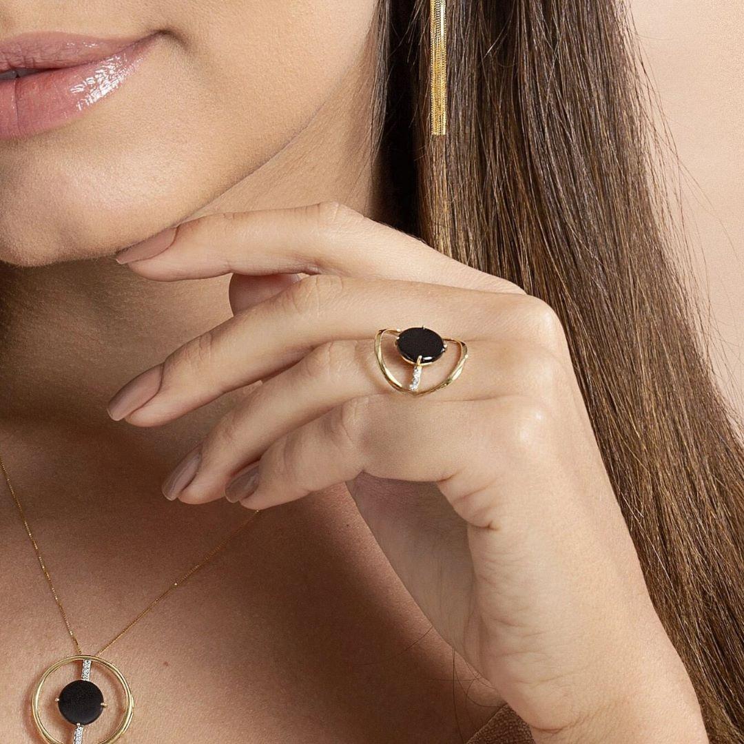 This bold 18K yellow gold ring features a striking black onyx centerpiece, framed with a unique open geometric design that makes an elegant yet contemporary statement. The onyx is securely prong-set, drawing all attention to its rich, deep hue. A