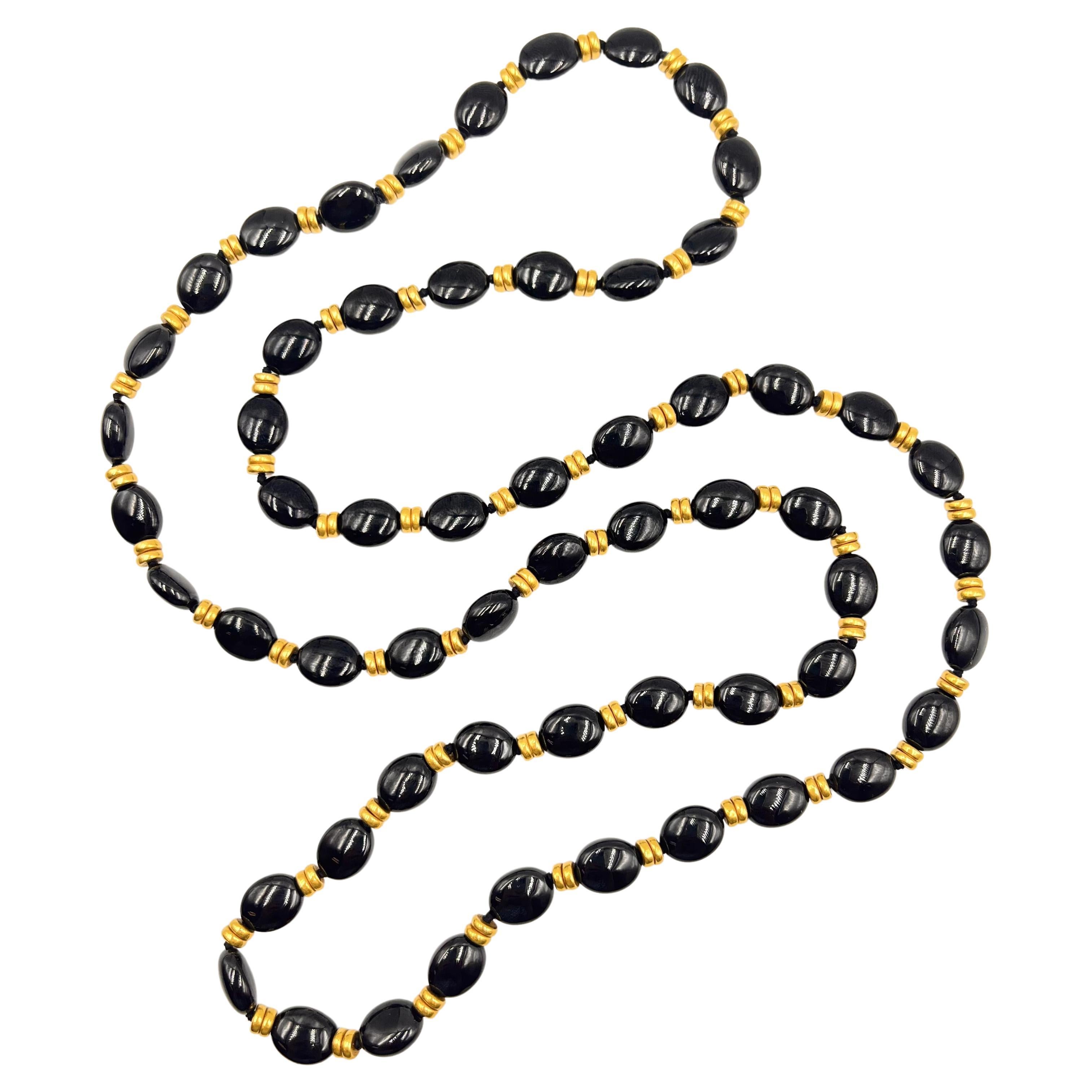 Long necklace, featuring a single-strand of fifty-eight oval black onyx polished beads with double rings of 18kt yellow gold rondelle-style beads set in between each.  Measuring 32