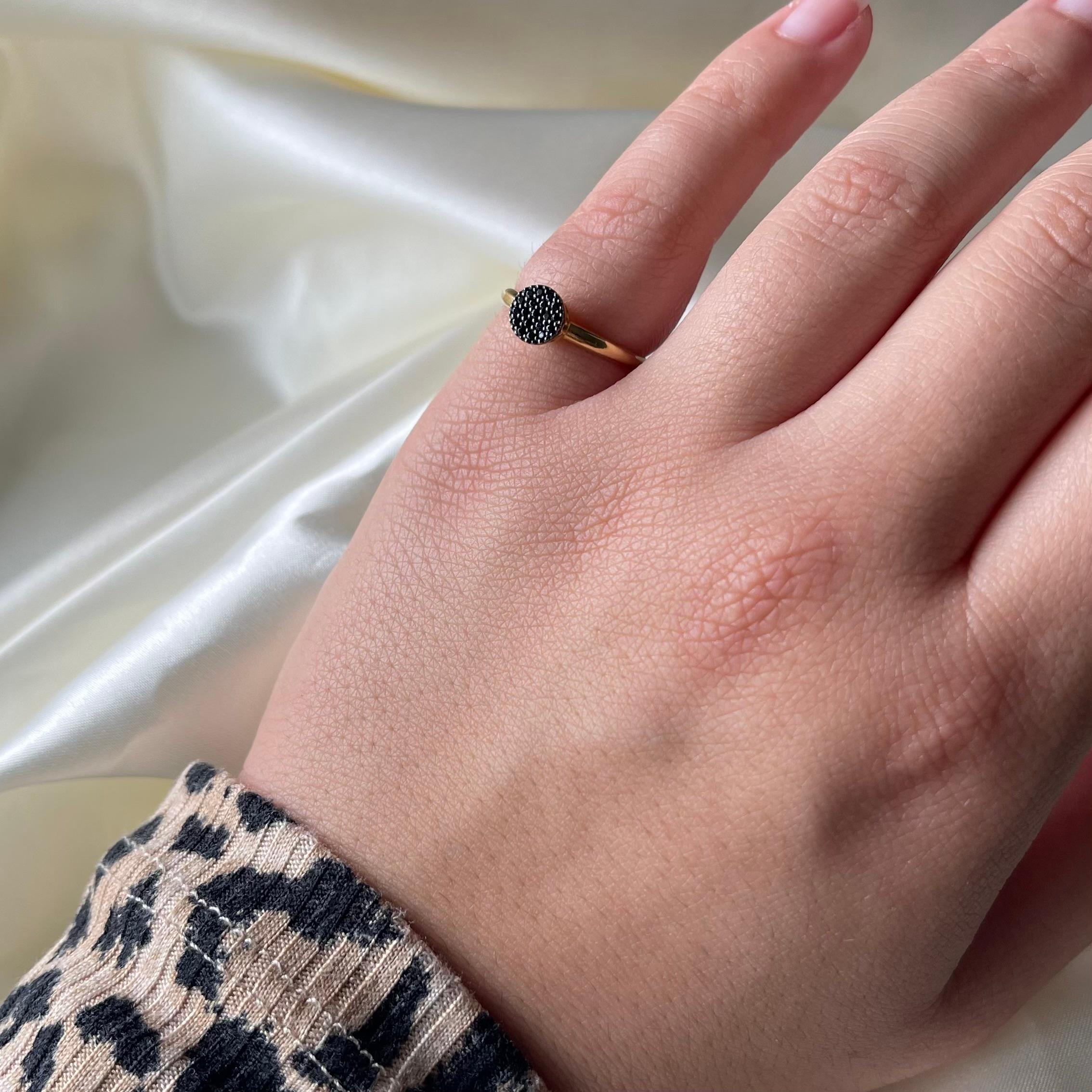 This sophisticated 18K yellow gold ring features a stunning circular setting encrusted with a pavé of black spinel gemstones. The pavé technique allows the black spinels to be set closely together, creating a surface that shimmers with brilliance.