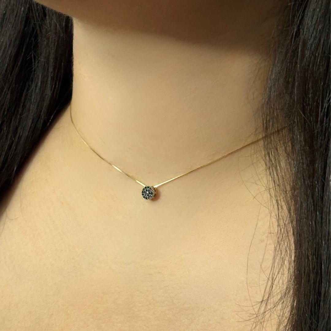 This elegant necklace features a circular pendant encrusted with black spinel gemstones, set in 18K yellow gold. The delicate chain is secured with a spring ring closure, providing both ease of wear and durability. The bold, sparkling black spinel