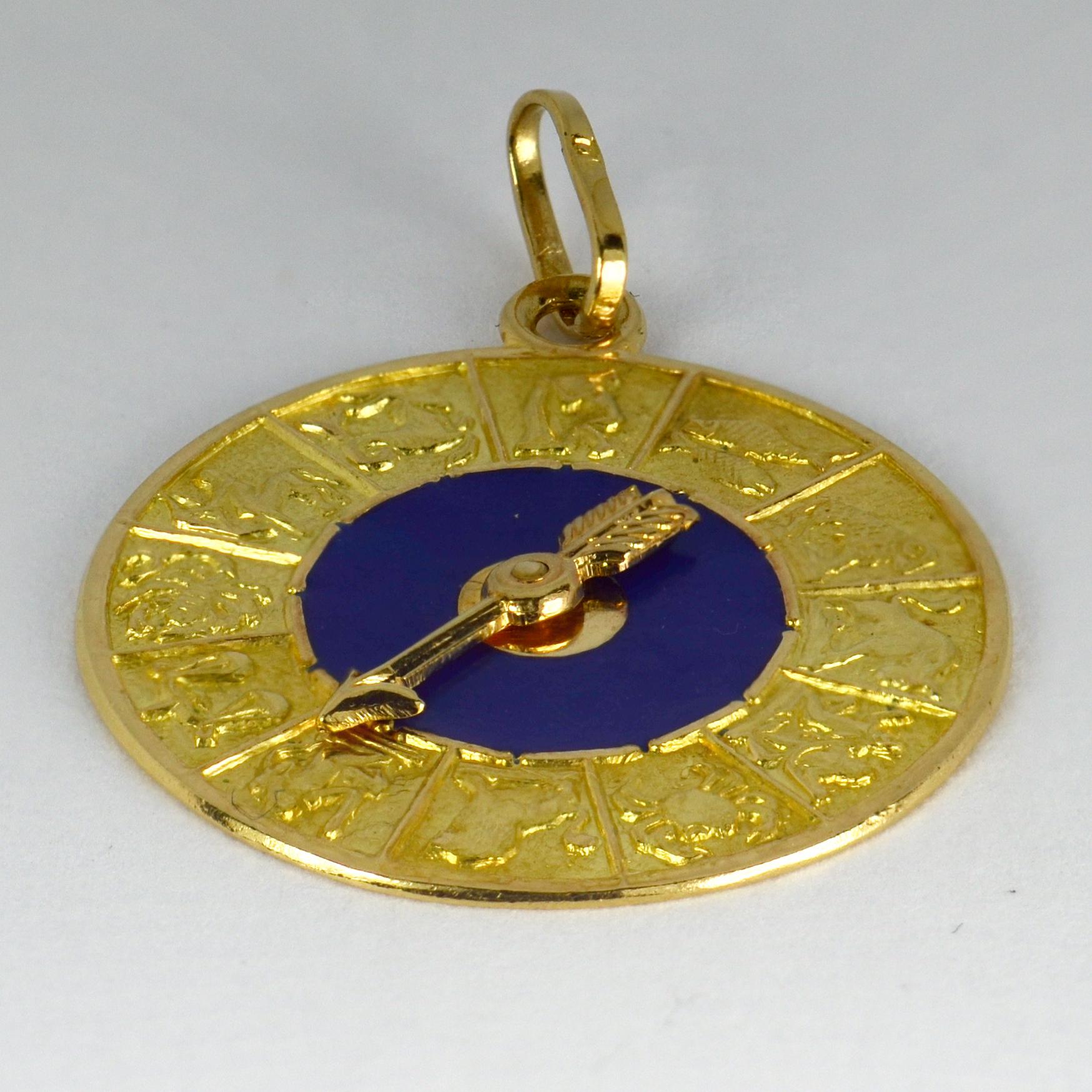 An 18 karat (18K) yellow gold and blue enamel charm pendant designed as a disc with a spinning arrow to point at one of the twelve starsigns of the Zodiac depicted around the edge. Stamped 750 for 18 karat gold and an unknown Italian maker’s