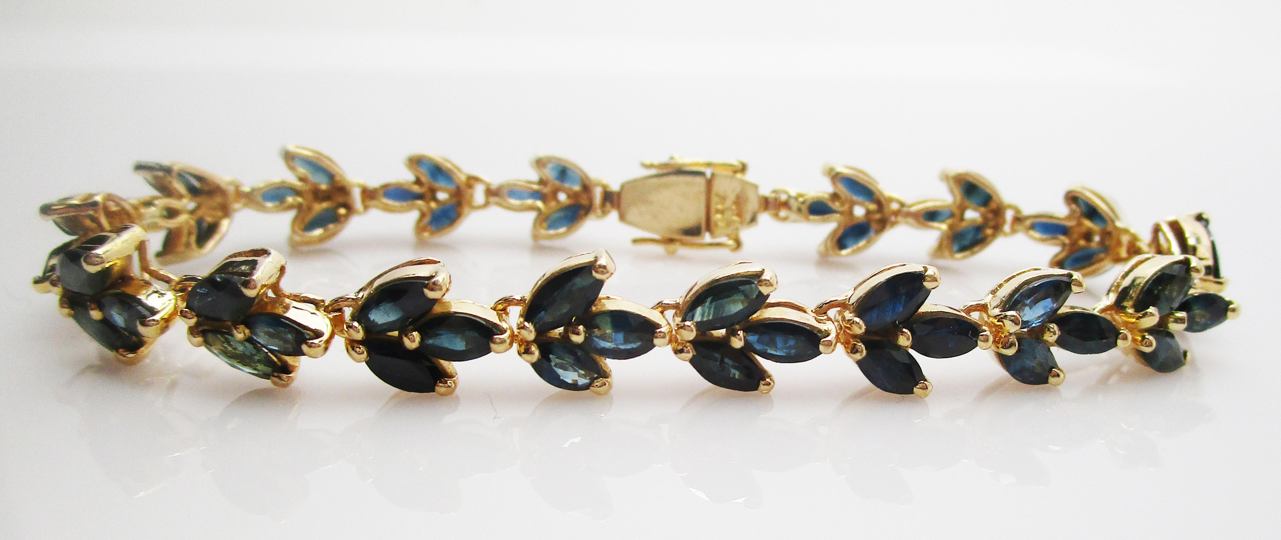 This is a lovely bracelet in 18k yellow gold with a stunning array of gorgeous blue sapphires! The marquise sapphires are set in a leaf-like pattern that creates a line bracelet that is a classic design with a unique twist! The combination of royal