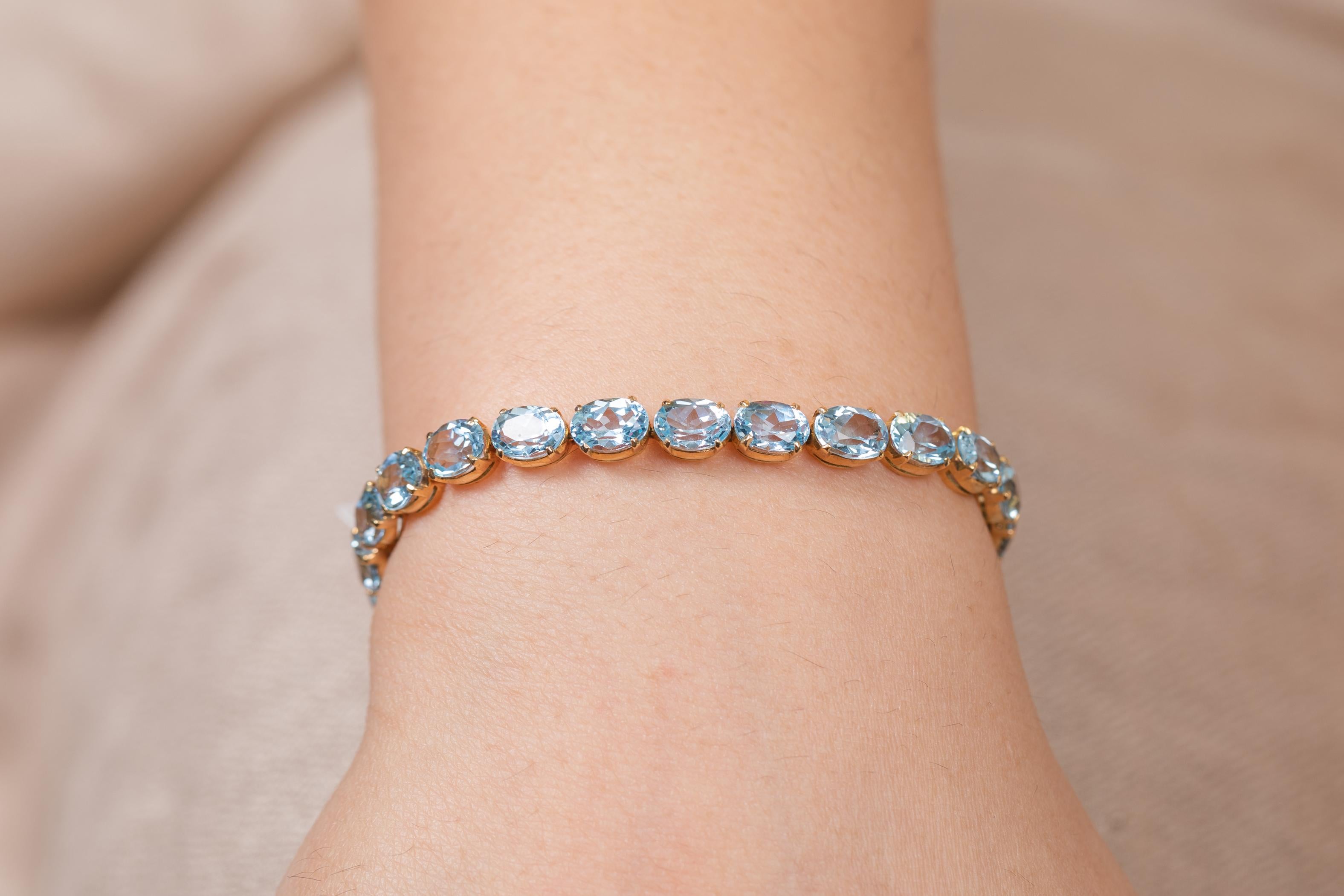 This Sparkling Blue Topaz Tennis Bracelet in 18K gold showcases 25 endlessly sparkling natural blue topaz, weighing 28.5 carats. It measures 7.5 inches long in length. 
Blue topaz helps to improve communication and self expression. 
Designed with