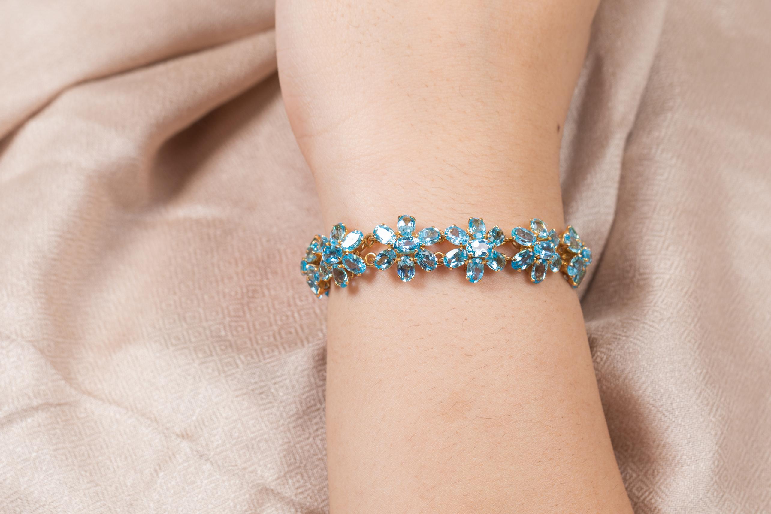 This Blue Topaz Flower Bracelet in 18K gold showcases 77 endlessly sparkling natural blue topaz, weighing 38.1 carats. It measures 7.5 inches long in length. 
Blue topaz helps to improve communication and self expression. 
Designed with perfect