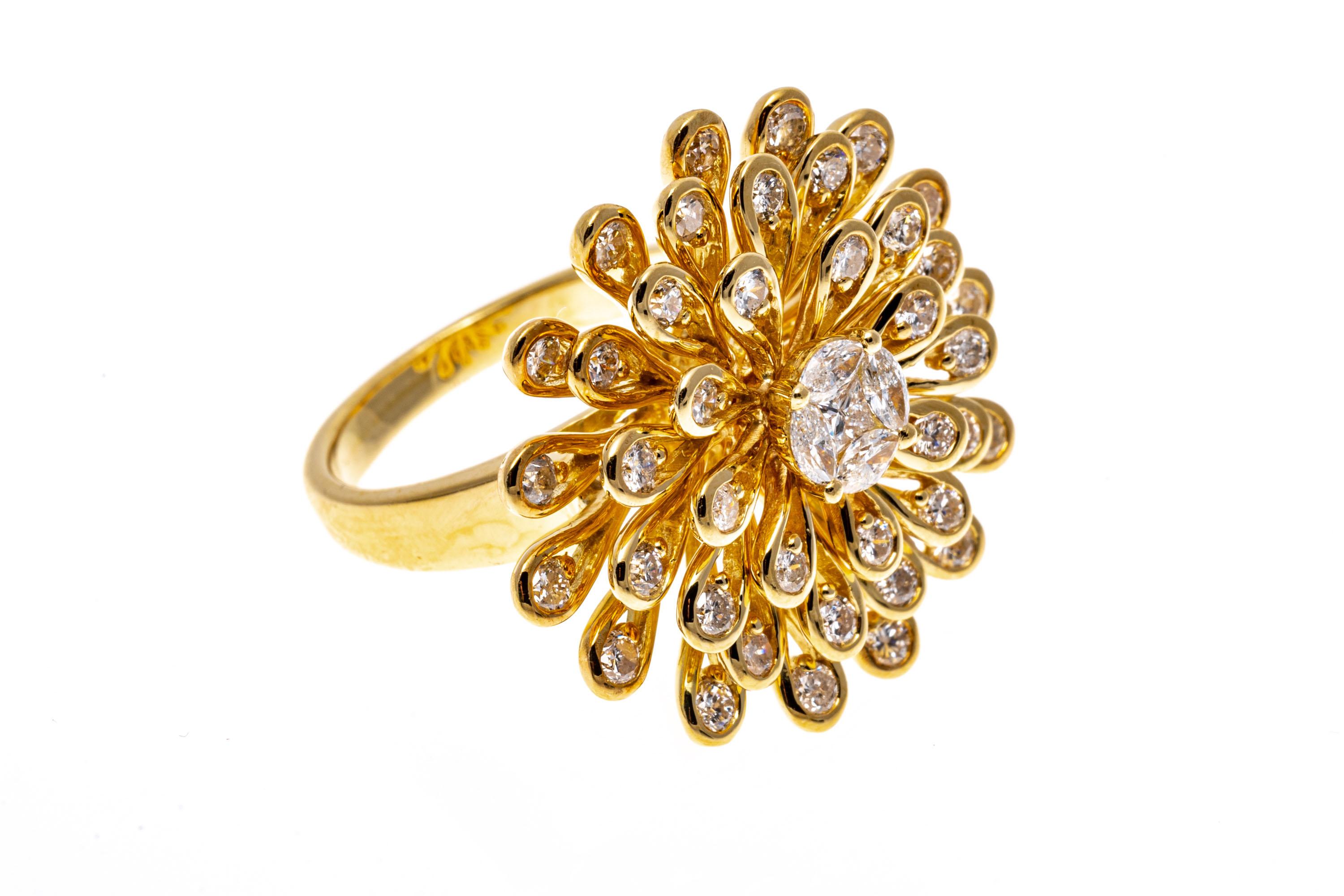 18k yellow gold ring. This delightful ring is a large zinnia flower motif, with a center featuring a princess cut diamonds, surrounded by four marquise brilliant diamonds, framed by a spray of petals, each set with a round brilliant cut diamond. The