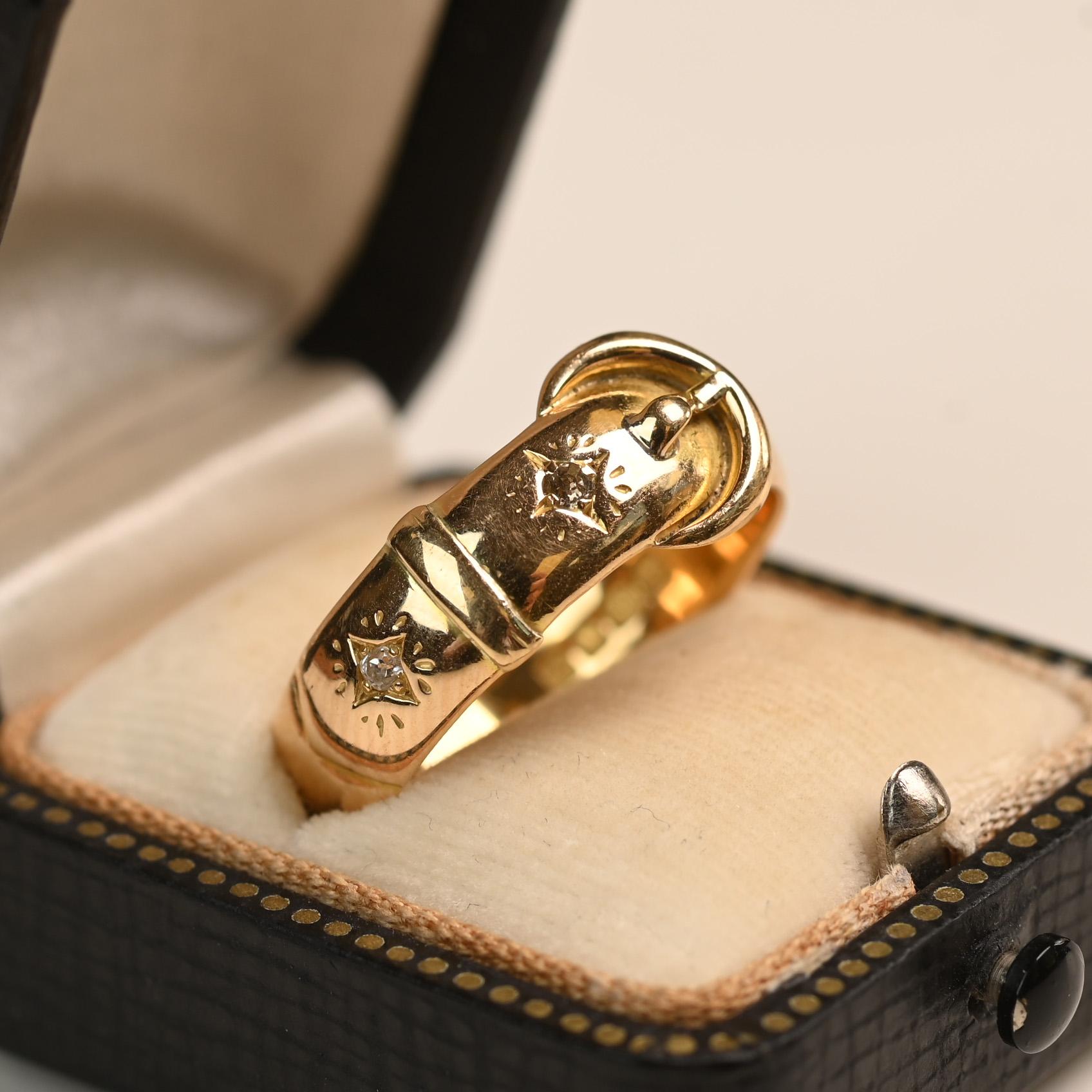 A striking English Victorian buckle band showcasing intricate gold detailing and timeless craftsmanship. Two sparkling diamonds accent the beltline, framed by finely hand-engraved patterns. Expertly crafted in rich 18k yellow gold, this piece dates