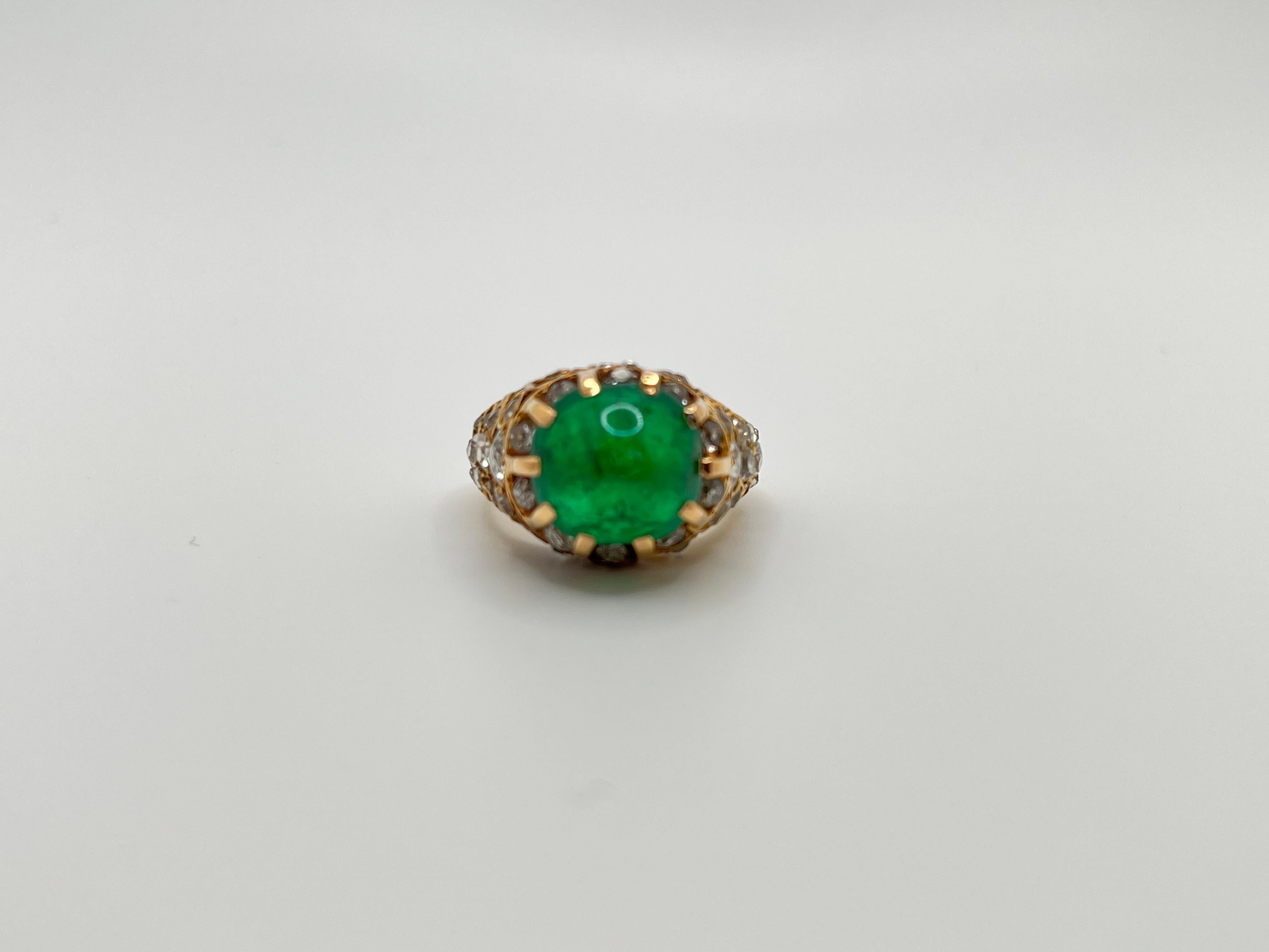 This exquisite cabochon emerald and diamond ring is hand-crafted in 18 karat yellow gold and is a product of the 1940s French jewelry craftsmanship. The centerpiece of the ring is a stunning cabochon emerald, surrounded by sparkling old mine cut