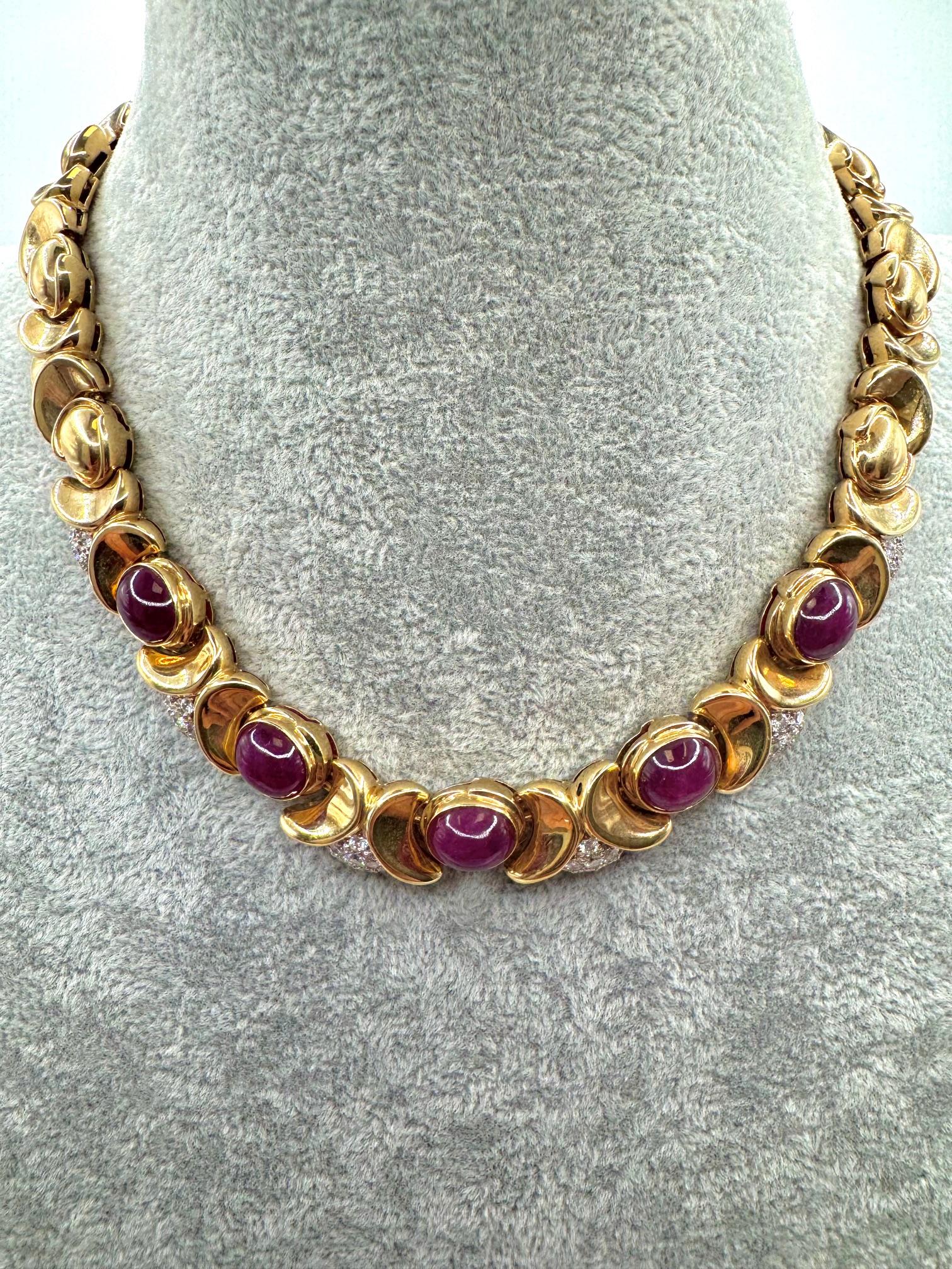 Llamativo y escultural, este collar vintage de los años 80 está elaborado en rico oro amarillo de 18 quilates y exhibe cinco rubíes cabujón de color rojo intenso con un peso total aproximado de 19,20 quilates. Cada rubí está engastado en un atrevido