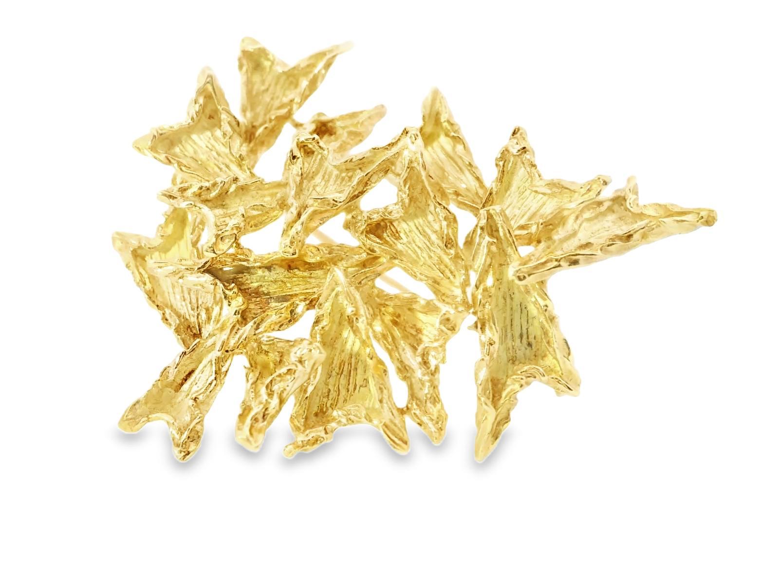 This striking brooch features an intricate design of overlapping leaf motifs, crafted in luxurious 18k yellow gold. The textured surface adds depth and dimension, enhancing the brooch's organic form.

The piece is meticulously detailed, showcasing