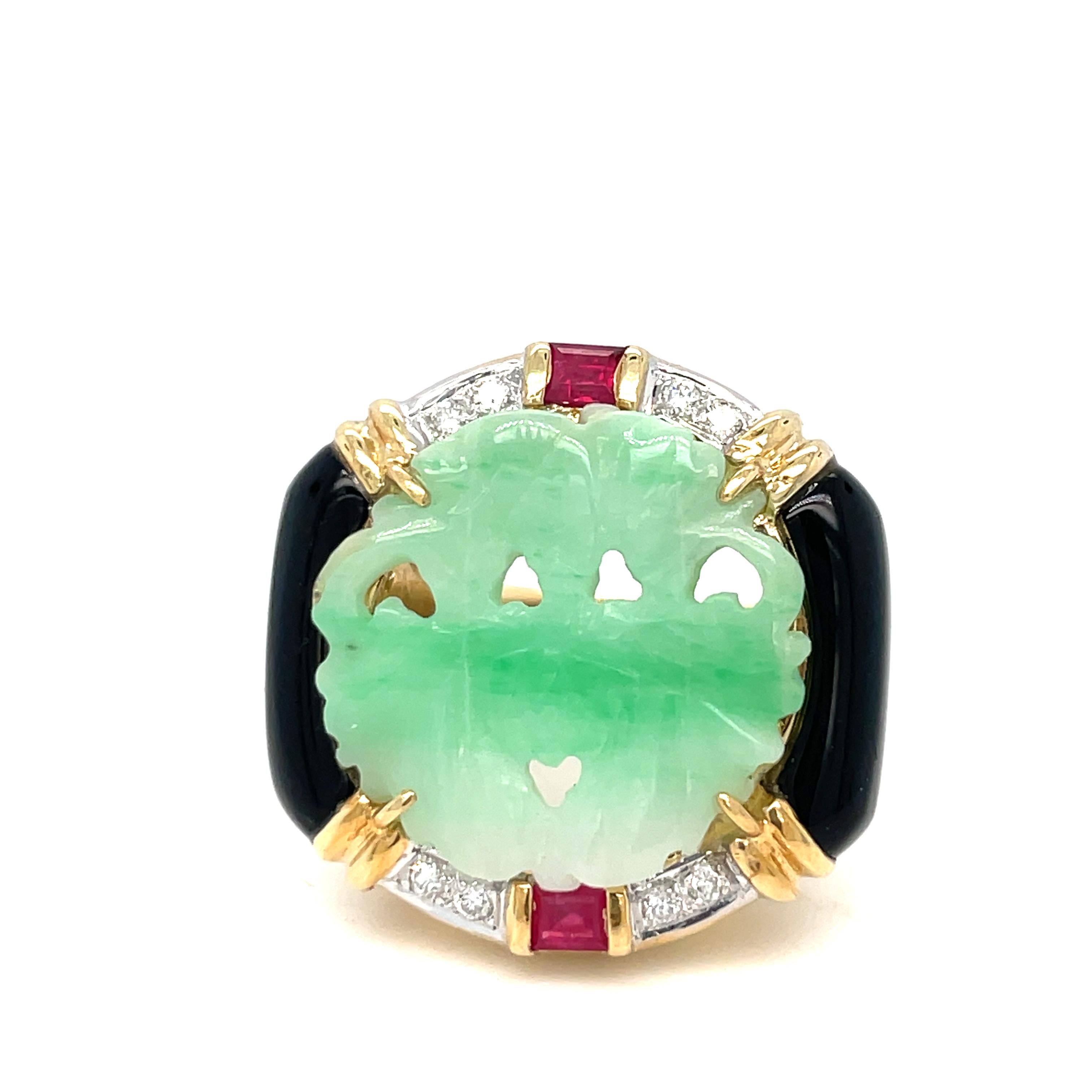 This gorgeous ring features a round-shaped plaque of hand-carved jade with an ornate oriental design, onyx, diamonds accented with 2 rubies, one on each side of the ring crafted in 18k yellow gold. 

The carved jade is prong-set, measuring 19.6 mm x