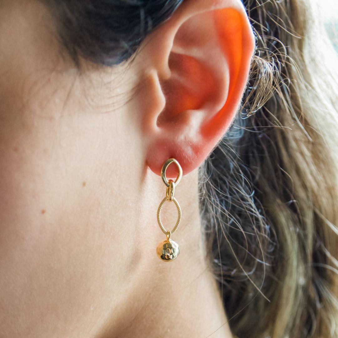 Ces boucles d'oreilles gouttes en or jaune 18 carats présentent une chaîne délicate avec une sphère polie à l'extrémité, dégageant une élégance discrète. Fabriquées à la main par des artisans qualifiés, le design est à la fois moderne et