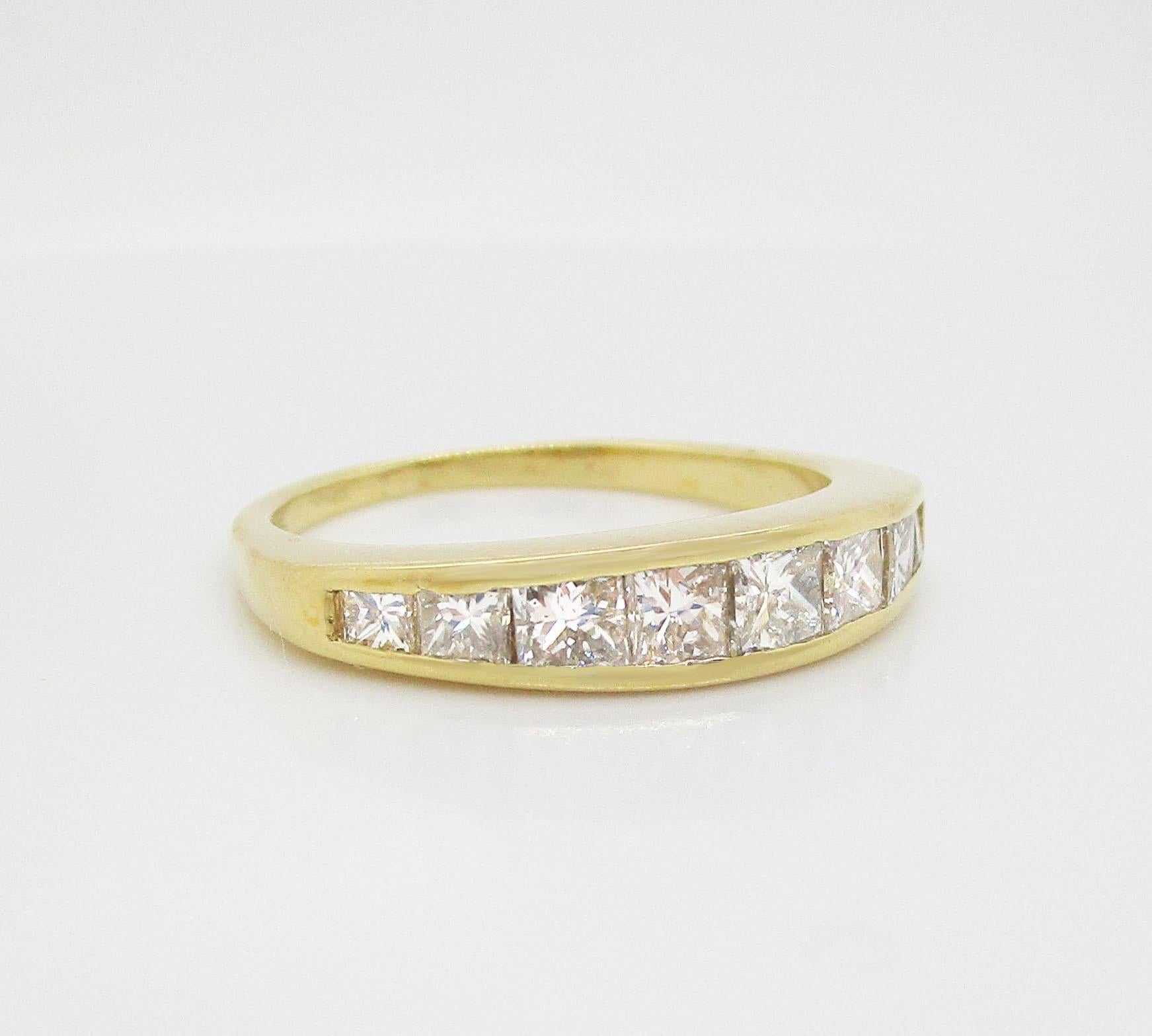 This is a gorgeous band ring in 18k yellow gold with a stunning array of channel set princess cut diamonds! The diamonds are arranged in a graduated layout that fits perfectly against the curve of the hand. This band would make the perfect stacking
