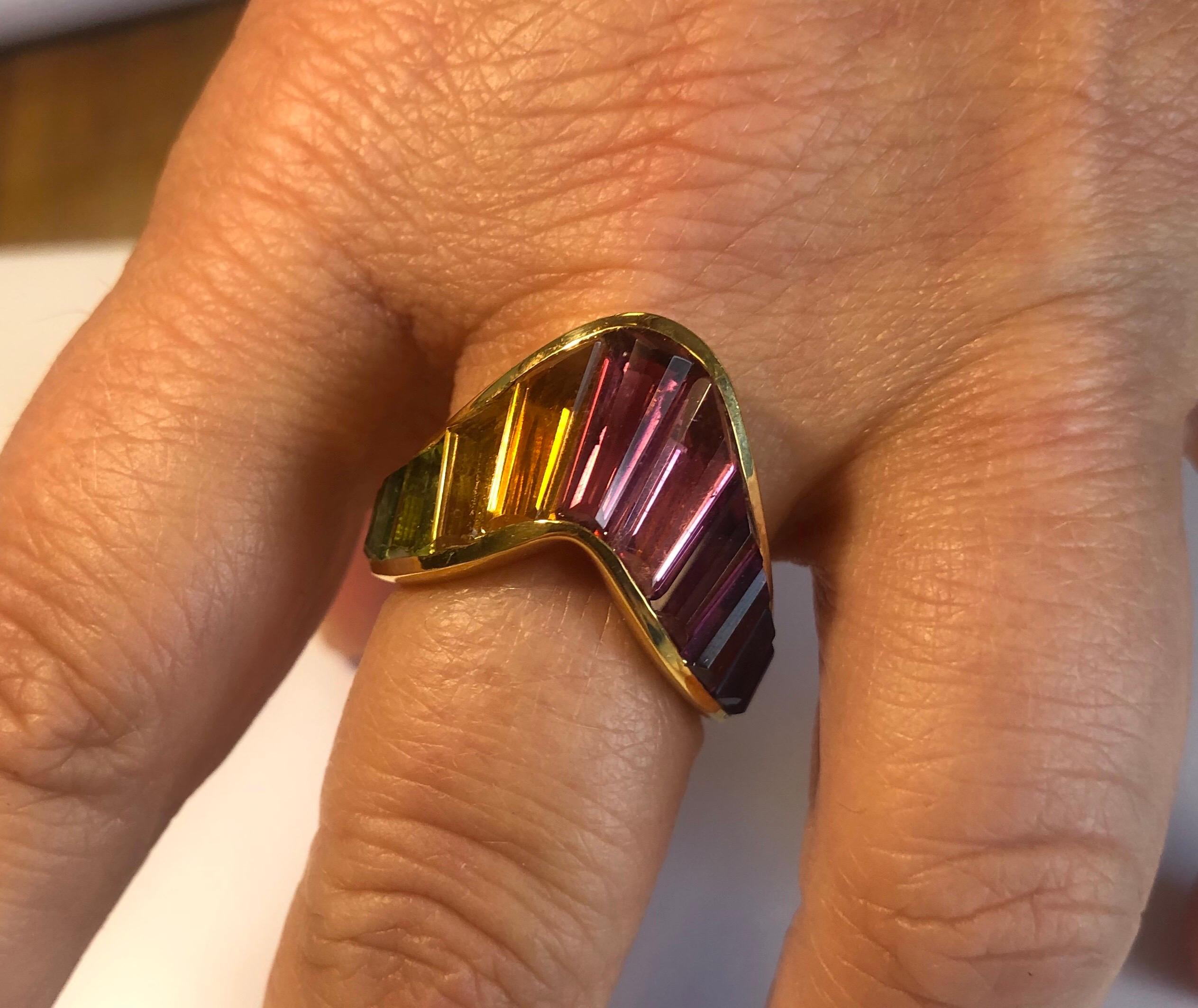 18K yellow gold Rainbow ring channel set with 11 specially cut faceted baguette shapes: pink and green tourmaline, amethyst, blue topaz, periodot and citrine.
Finger size 7, may be sized smaller or larger.
Last retail $5500