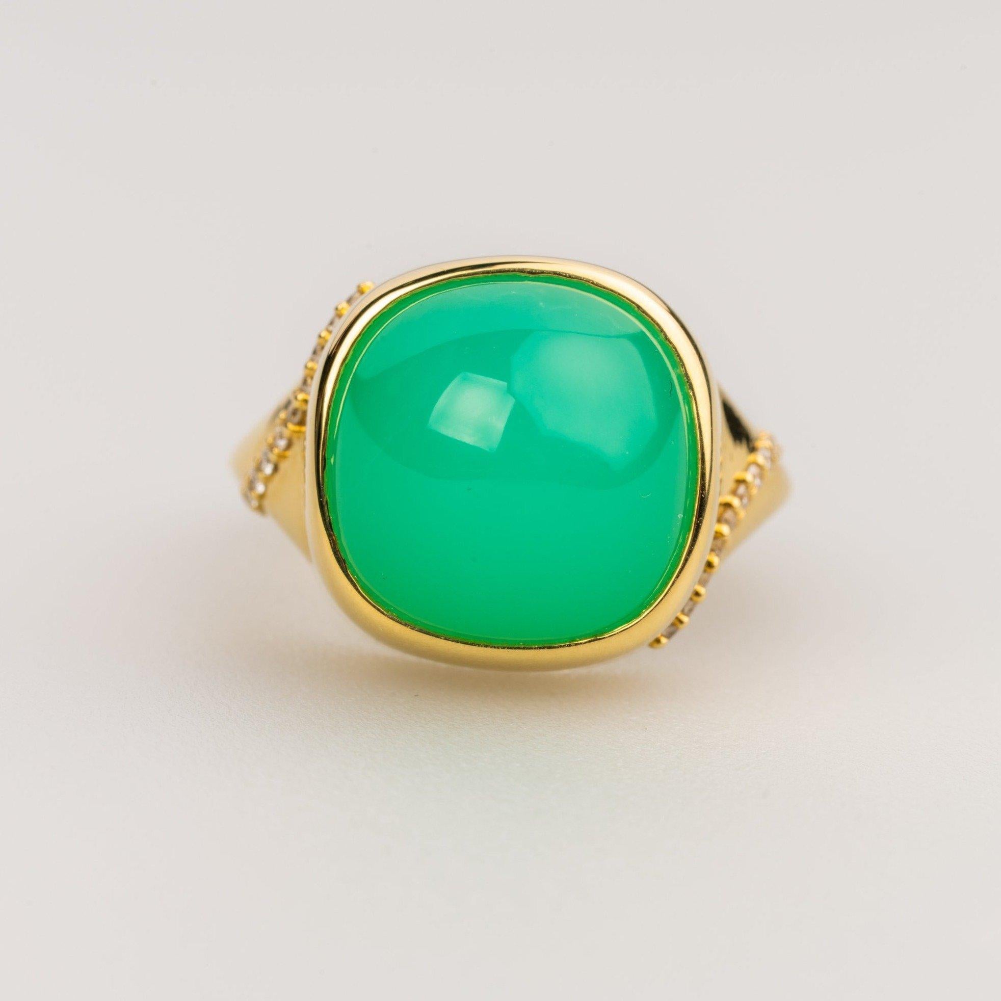 An 18k yellow gold ring featuring one bezel set cushion cut green chrysoprase and accented by 22- 1mm round full cut white diamonds F color VS clarity .11 carats. Ring size 7. This ring was designed and made by Sydney Strong.