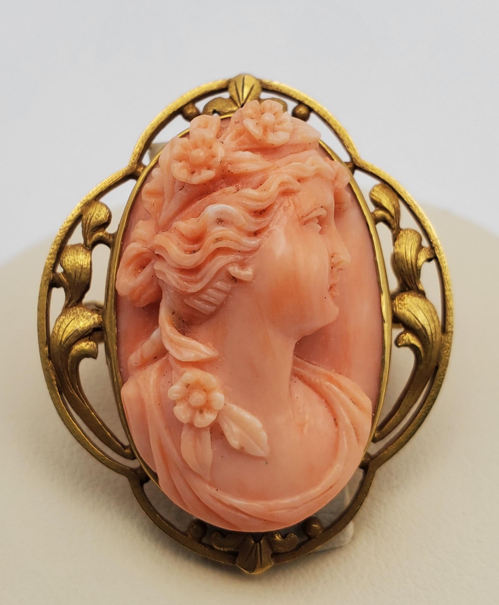 18K Yellow Gold Classic Beauty Natural Coral Cameo Convertible Pendant/Brooch from approximately the 1890s. The brooch consists of a oval shaped bezel set natural coral cameo in a filagree elongated quatrefoil shape. The cameo is a lovely carving of