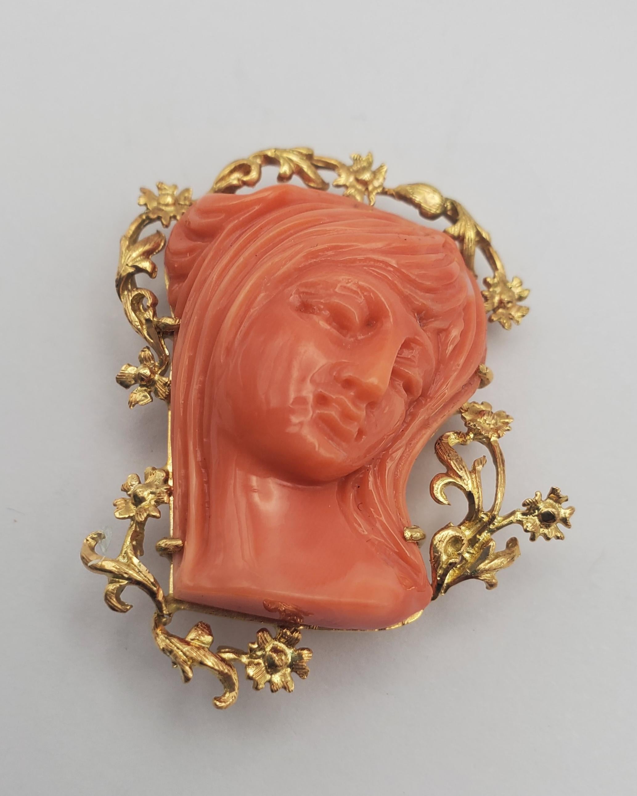 18K Yellow Gold Classic Beauty Natural Coral Cameo Convertible Pendant/Brooch from approximately the 1890s. The brooch consists of a vibrantly colored natural coral cameo wreathed with detailed flowers carved in 18k yellow. The cameo is a lovely