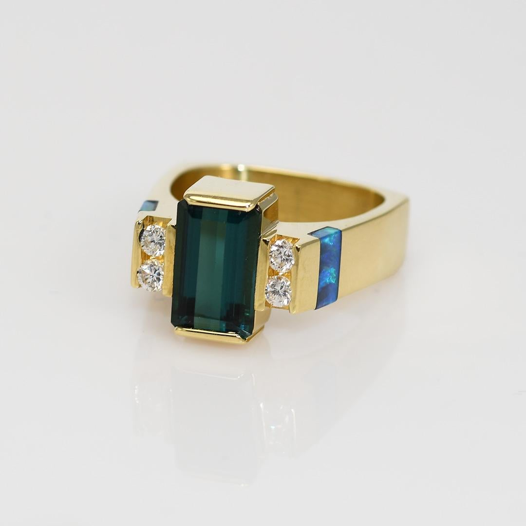 Ladies tourmaline, diamond and opal custom made ring in 18k yellow gold.

Stamped 18k and weighs 11.9 grams gross weight.

The gold tests 73% gold with an XRF metals analyzer.

The tourmaline is a strong bluish-green color, 2.50 carats.

On the