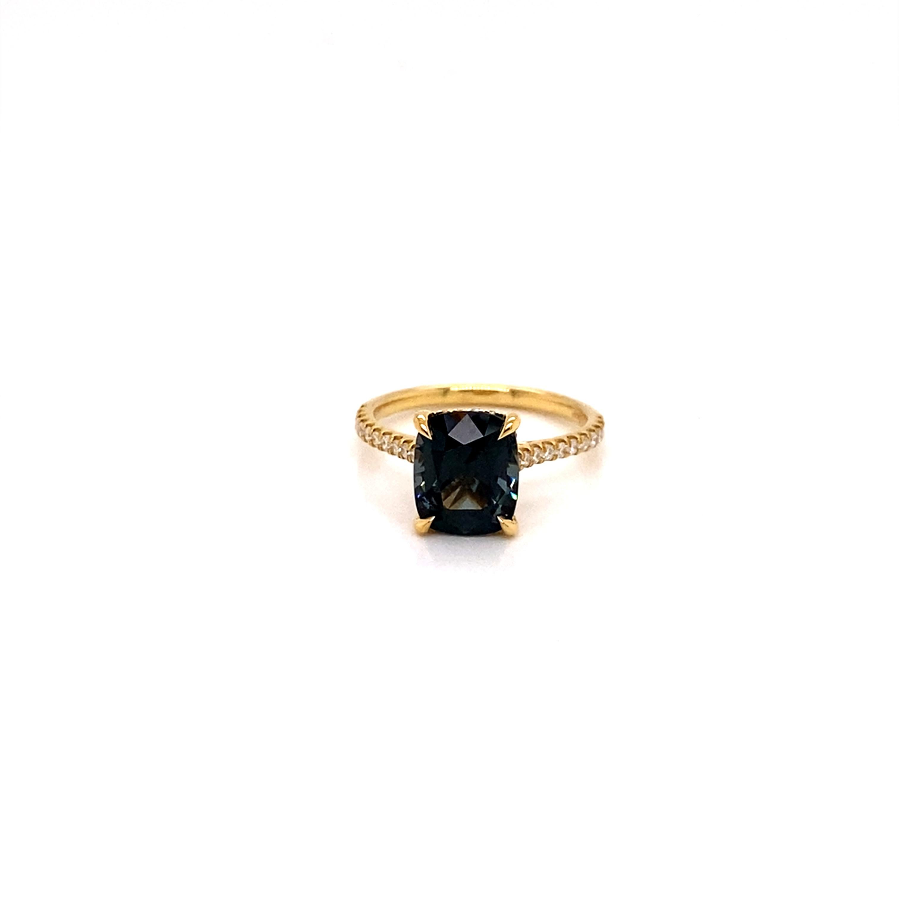A stunning 3.03ct Smoky Teal Spinel is the center piece if this wonderfully glamorous ring. 
The natural spinel is set in high polish 18k yellow gold band and accentuated with both shimmering diamonds on the band and a luxurious hidden diamond halo