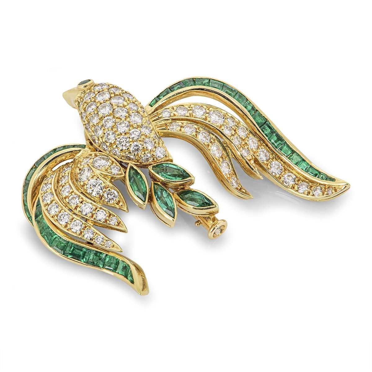 A unique 18k yellow gold diamond and emerald brooch. The brooch comprises of a bird motif with moving wings. The motif has 81 round brilliant cut diamonds in a pave setting through the body and wings with a round brilliant cut emerald as the bird's
