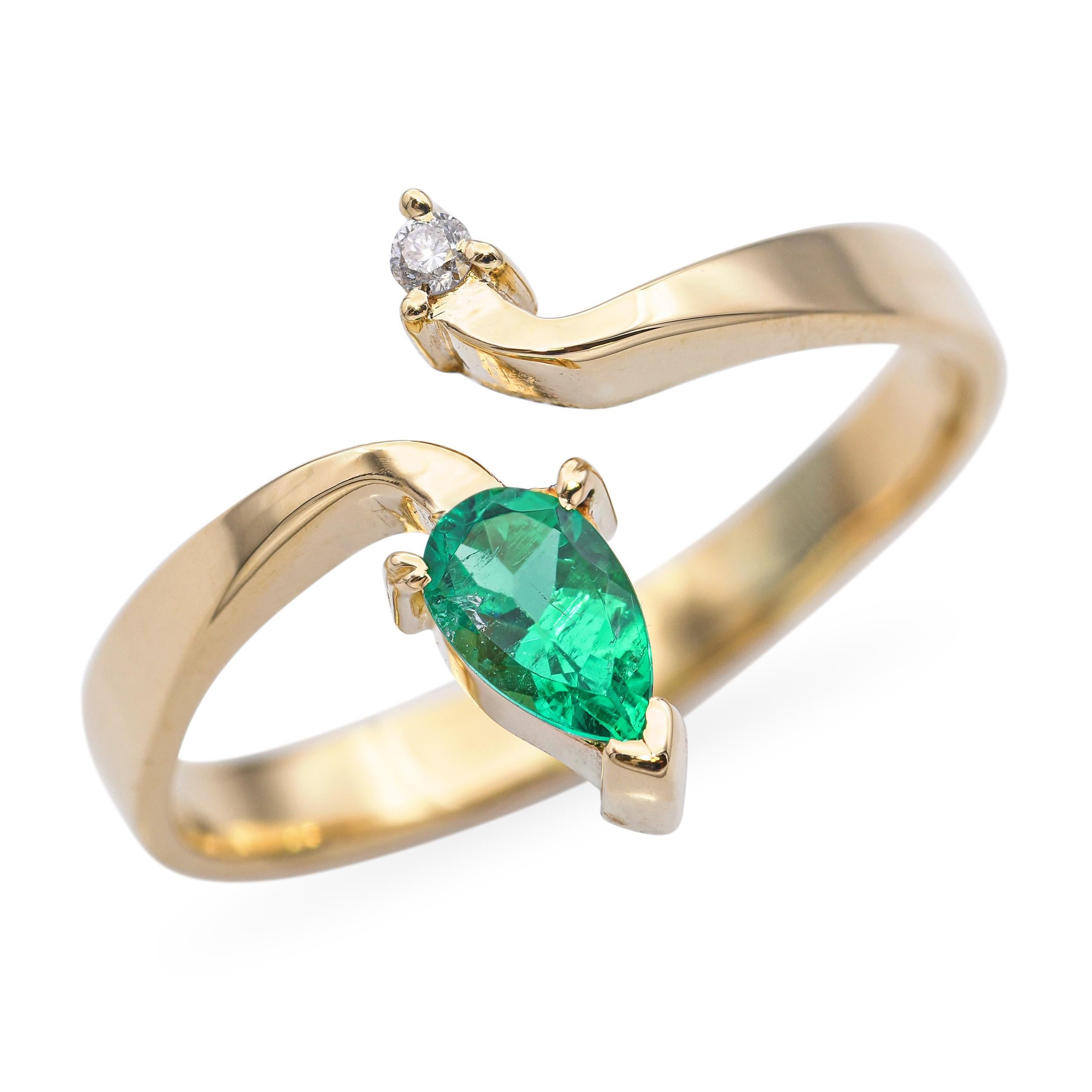 Anello bypass in oro giallo 18 carati con un brillante diamante abbinato a un vibrante smeraldo. Il grazioso design della circonvallazione simboleggia l'unità e il movimento, incorniciando splendidamente il contrasto di brillantezza delle due