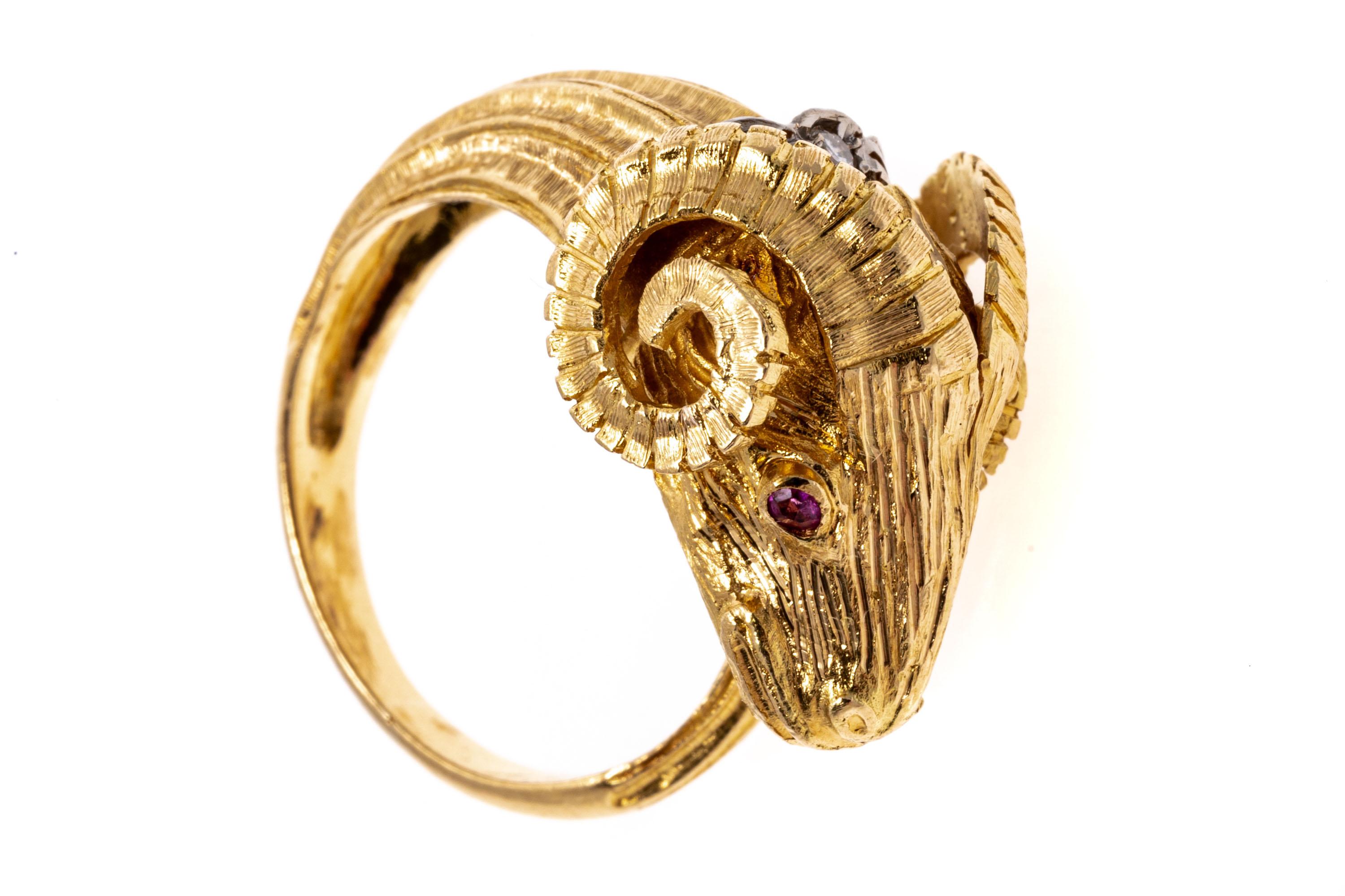 Created in Greece, this 18K yellow gold ring features the head of a ram with the tail wrapping around the finger. Set into the eyes of the ram are round cut rubies while a single brilliant round cut diamond is set at the back of the head. The rubies