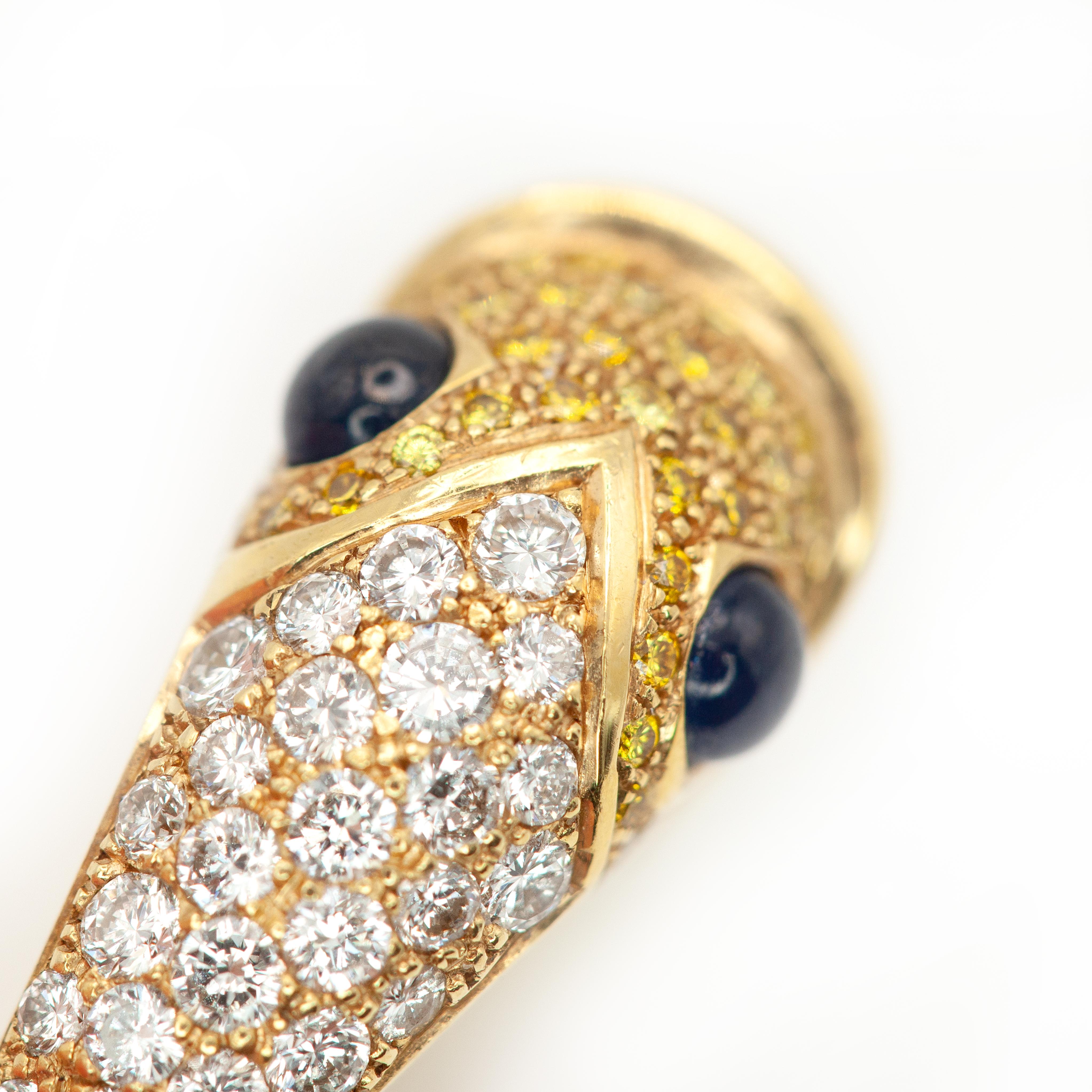 Setzen Sie ein Zeichen mit diesem exquisit gearbeiteten, skulpturalen Ring aus 18 Karat Gelbgold, der die Form eines stilisierten Fisches hat. Kopf und Körper sind mit 71 Diamanten im Brillantschliff und gelben Diamanten besetzt. Cabochon-Saphire