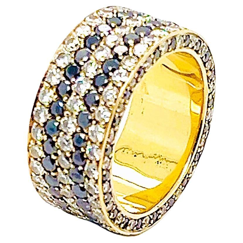 Elevate your jewelry collection with this exquisite 10mm wide band crafted in 18k yellow gold. This mesmerizing piece features three rows of white diamonds and two rows of black diamonds, elegantly interchanging around the ring and on the sides.