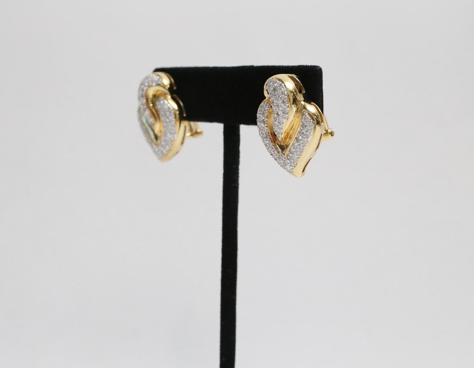 Estos elegantes pendientes de diamantes de oro de 18k destilan sofisticación y lujo atemporales. Con forma de corazón escultural, el diseño presenta amplias curvas que entrelazan oro amarillo pulido con hileras de diamantes talla brillante. El