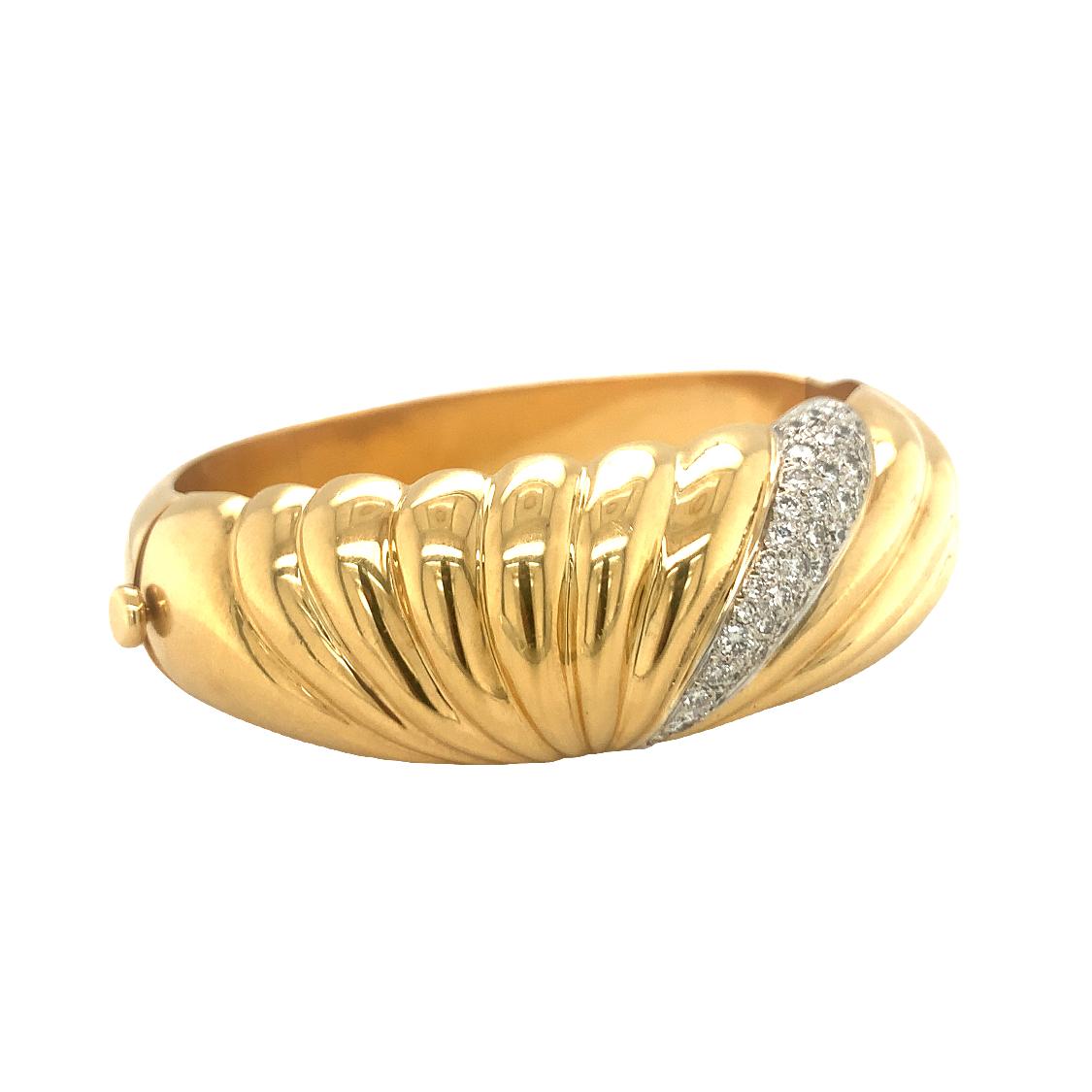 Scultoreo e sofisticato, questo braccialetto bangle vintage in oro giallo 18 carati è un richiamo all'audace design degli anni '70-'80. La sua spettacolare silhouette a cupola è rifinita in un ricco oro lucido, accentuato da una struttura