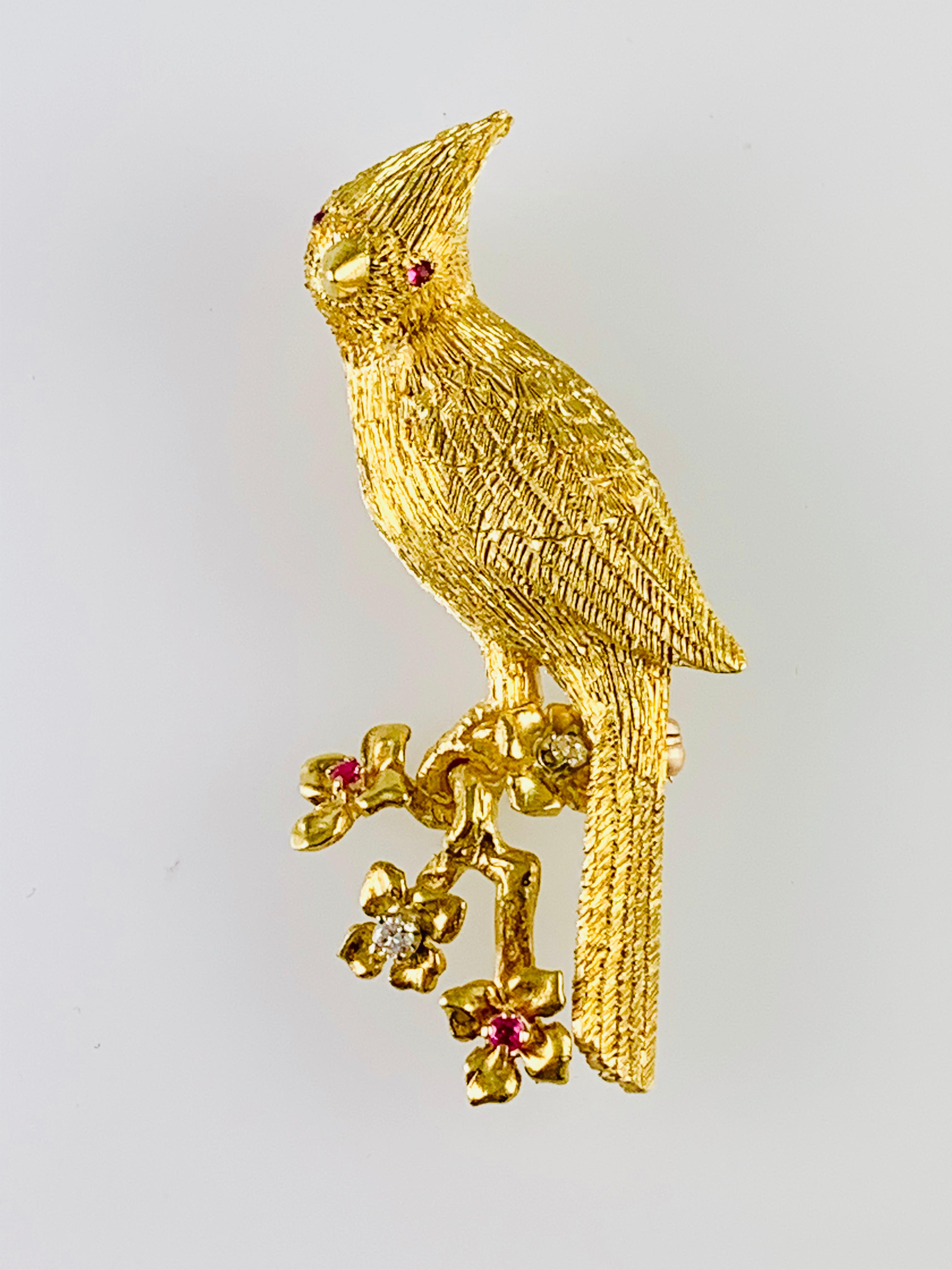 Gorgeous Bird Brooch! made in 18K yellow Gold. It has Bright Ruby Eyes and then two diamonds and two rubies in the flowers on the branch. The brooch  measures 2 inches by 1 inch and weighs 15.7 grams. The workmanship on this piece is simply