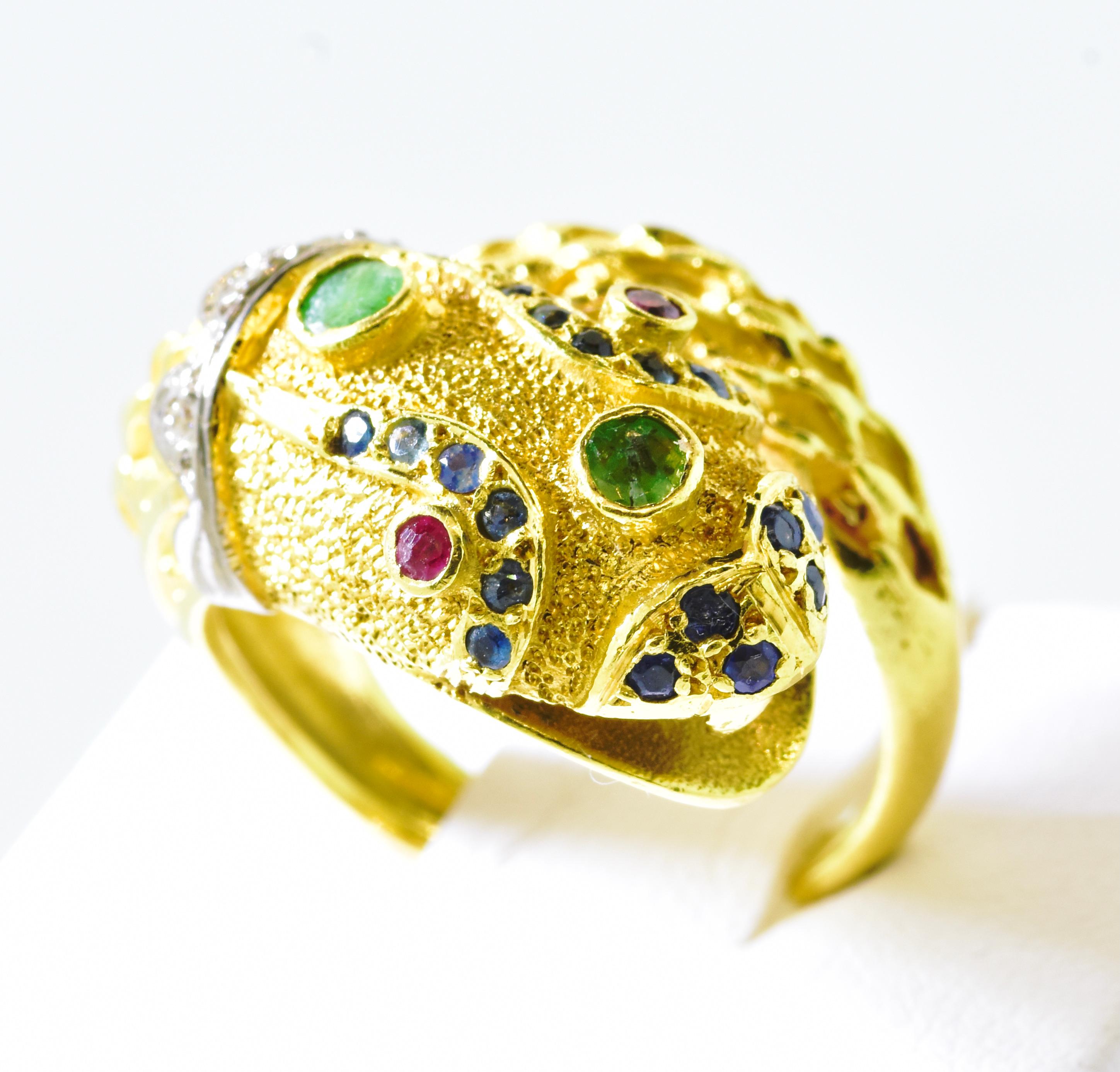 18K snake ring possessing 2 natural vivid red ruby eyes, 2 natural green emeralds set on his head, 3 brilliant cut white diamonds set in 18K white gold, and 18 blue round sapphires.  This multi gem happy snake - which symbolizes rebirth and new