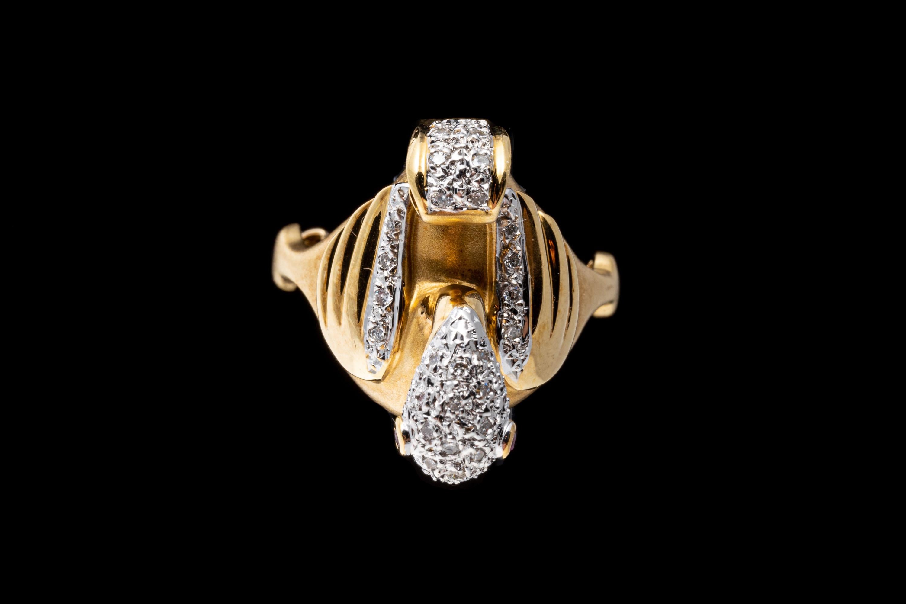 18k yellow gold ring. This playful ring is a figural flamingo, decorated with high polished wings, adorned with round faceted diamond trim, with a pave diamond head and tail, embellished with round faceted ruby eyes, approximately 0.02 TCW. The