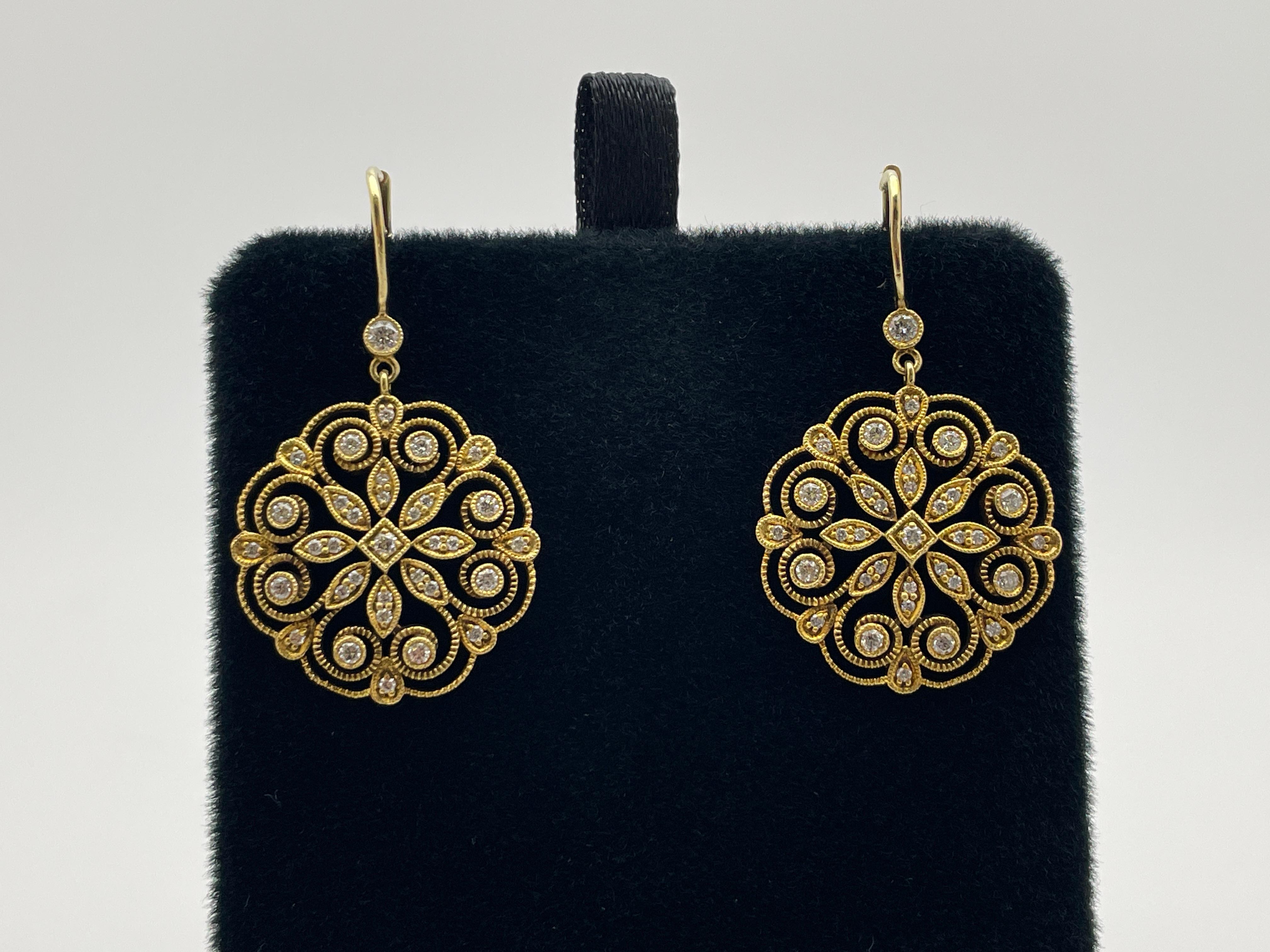 An original pair of 18K yellow gold diamond textured snowflake/floral design earrings. Mounted with a total of 68 round brilliant cut diamonds weighing a total of approximately 1.25 CT, G color (aprox), VS1 clarity (aprox). 

A gorgeous subtle
