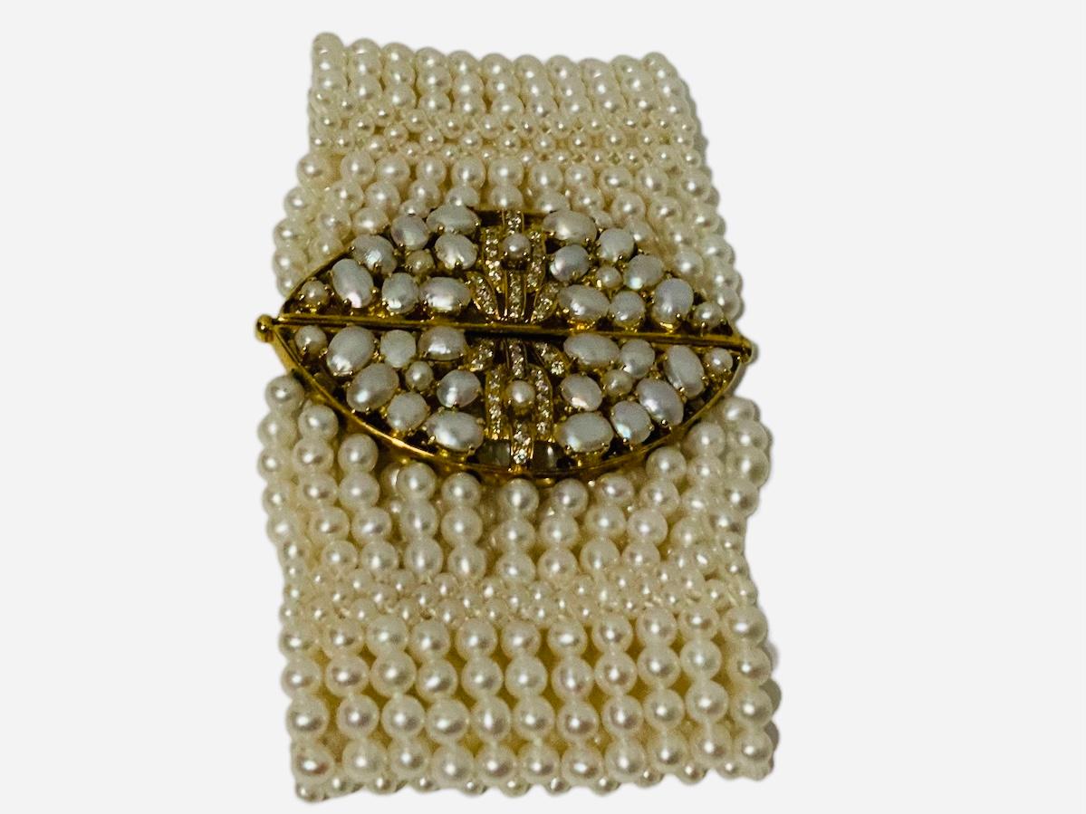 Dies ist ein 18K Gold Armband aus Perlen und Diamanten. Das Armband besteht aus mehreren Perlensträngen, die in der Mitte mit einer marquiseförmigen Brosche verbunden sind. Diese Brosche ist in vier dreieckige Felder unterteilt, die  besteht aus