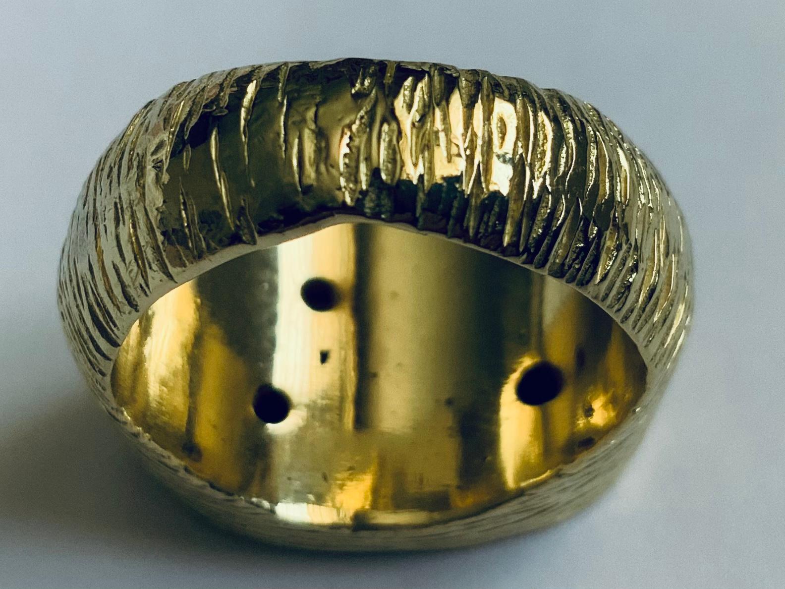 This is an 18K Yellow Gold Diamonds Men Ring. The ring has three round diamonds ( 7 pt each one ) embedded and adorning an oval gold rocky top surface of the ring. The shanks of the ring have a Florentine texture like. They are mount made in 18K