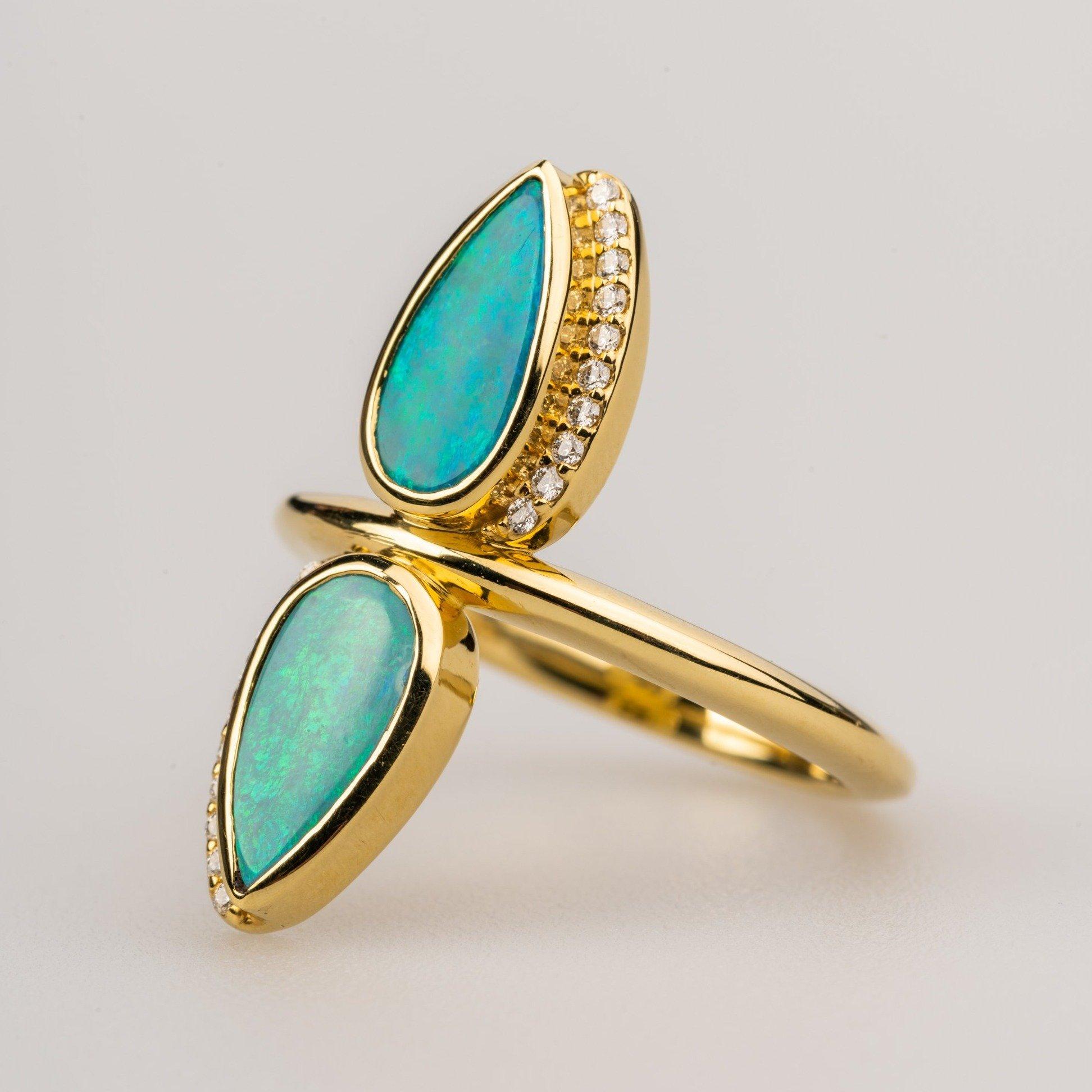 An 18k yellow gold ring featuring 2 pear shaped opal doublets and accented by .10 carats of round full cut white diamonds F color VS clarity. Ring size 6.75. This ring was made and designed by Sydney Strong.