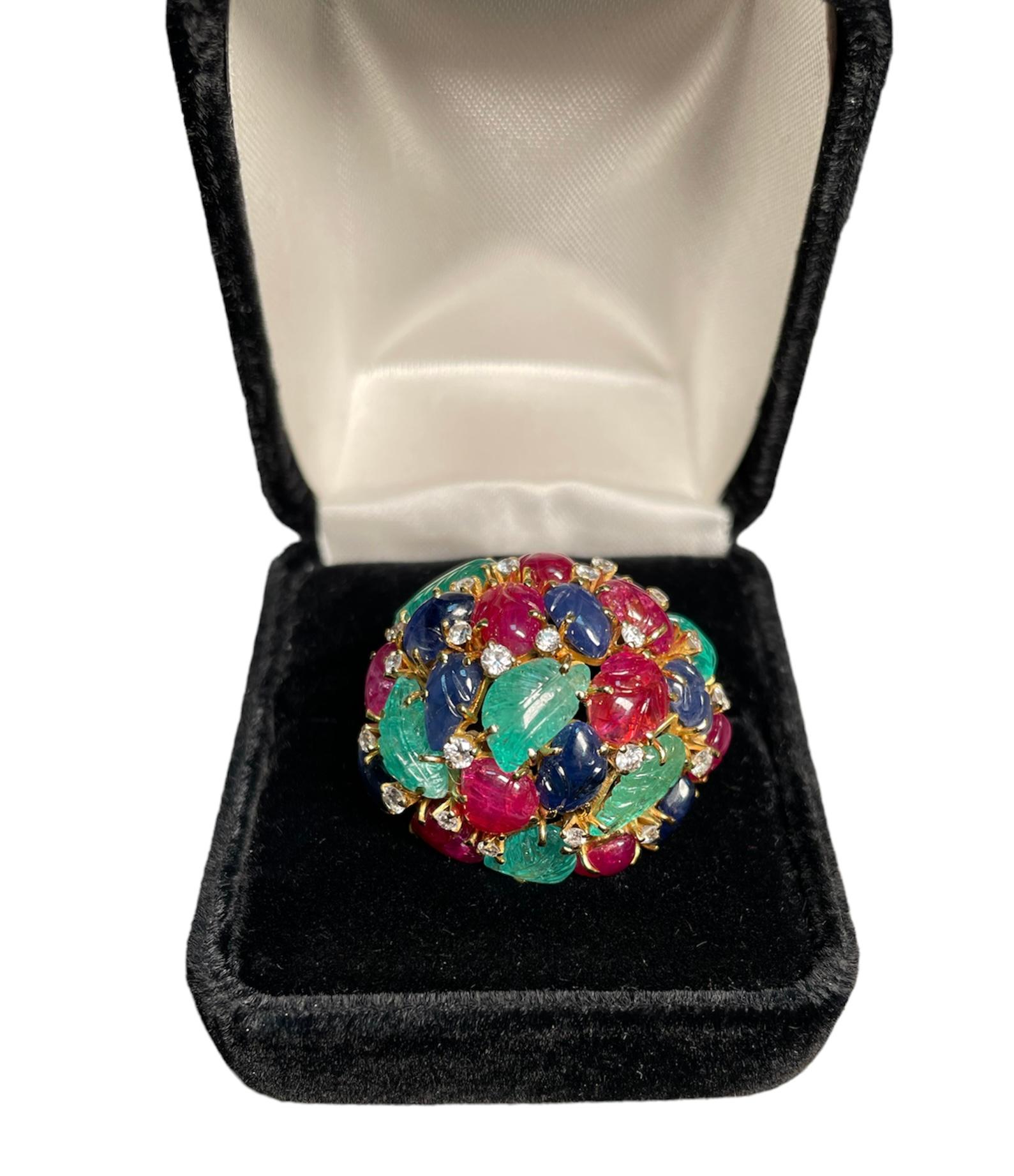 This is an 18k yellow gold 45.80 ct (gemstones) Tutti-frutti cocktail ring. It depicts a dome made of polychromatic mosaic of hand carved leaves made of different gemstones. This mosaic of gemstones are green emeralds (6), red rubies (9) and blue