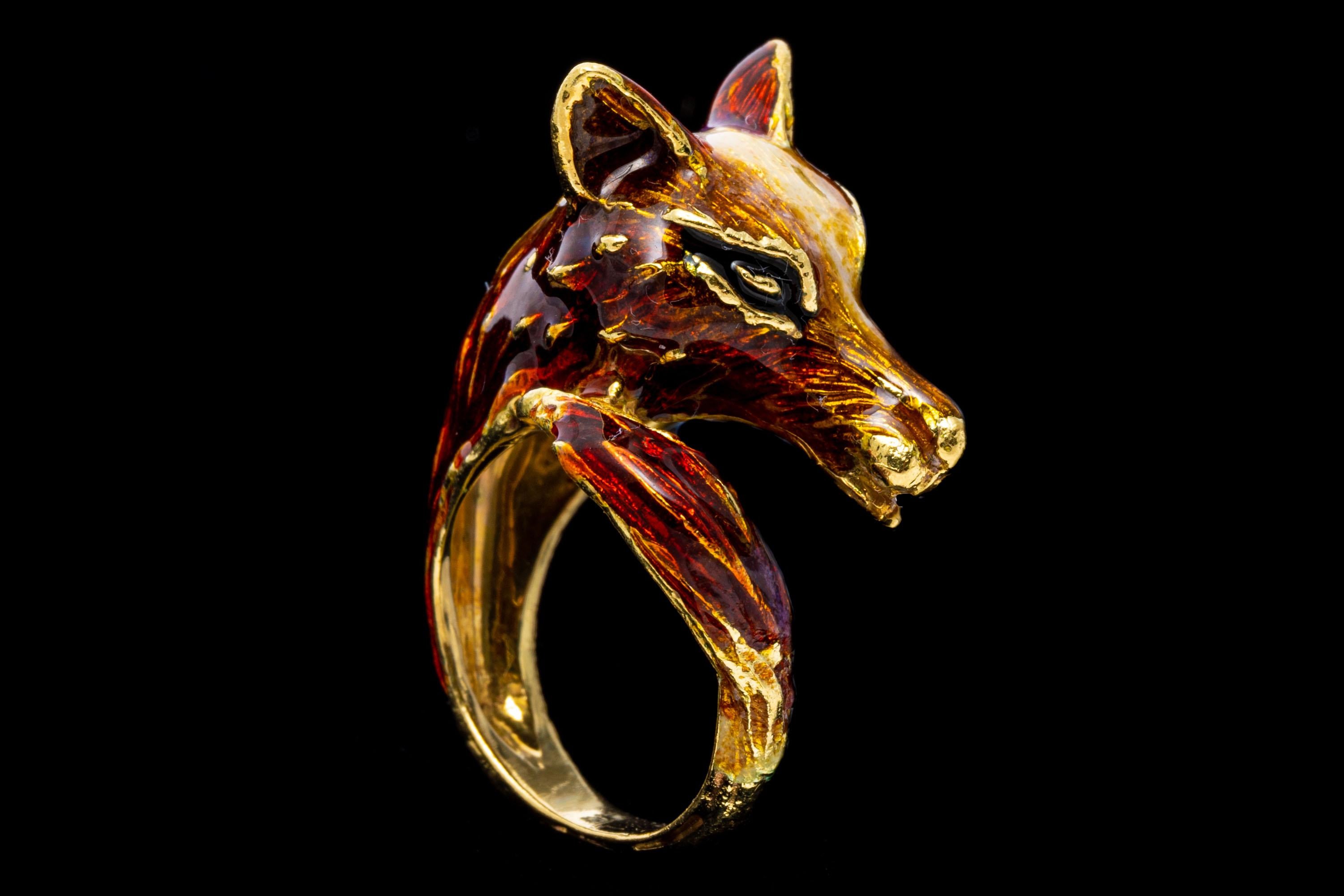 18k yellow gold ring. This unique ring is a yellow gold center figural fox head that curls back on itself to the tail, set with a reddish brown color enamel and decorated with a white enamel striped head.
Marks: 750
Dimensions: 7.8