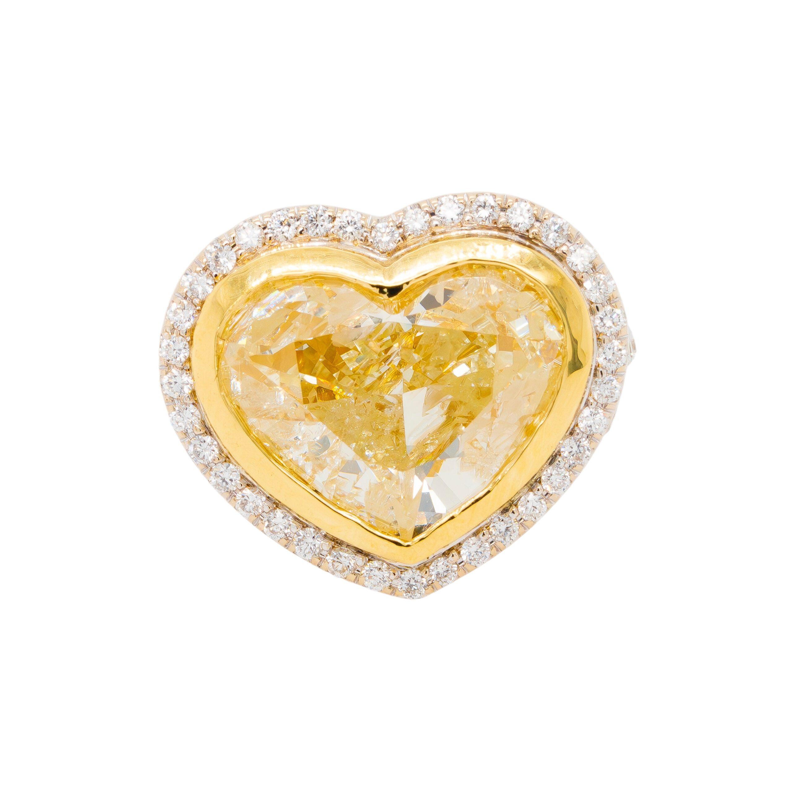 Cette époustouflante bague en or blanc 18 carats est sertie d'un superbe diamant en forme de cœur de 8,32 carats de couleur jaune fantaisie qui rayonne de chaleur et d'éclat. Entourée d'environ 1,98 carats de diamants ronds naturels de taille