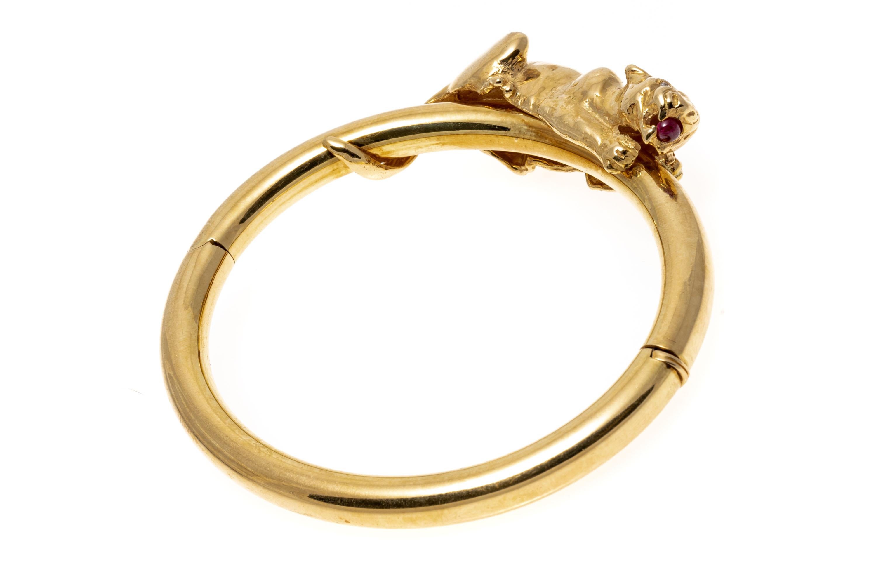 18k Yellow Gold Wonderful Figural Crouching Panther Hinged Bangle Bracelet.
This wonderful hinged bangle bracelet features a high polished, wide tube style bracelet, decorated with a figural crouching tiger top, with diamond eyes, approximately 0.02