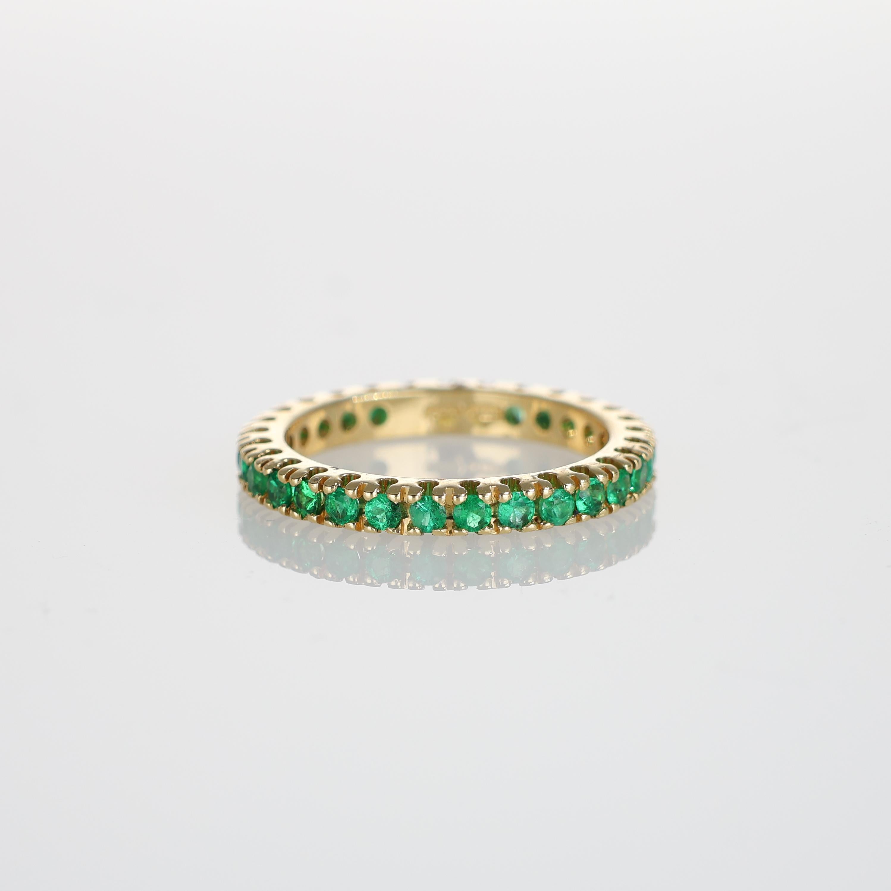 A timeless full eternity band crafted in 18K yellow gold, set with 29 vivid emeralds totaling 0.90 carats. The continuous row of gemstones enhances the elegance of this piece, making it a refined choice for stacking or wearing alone. A delicate yet