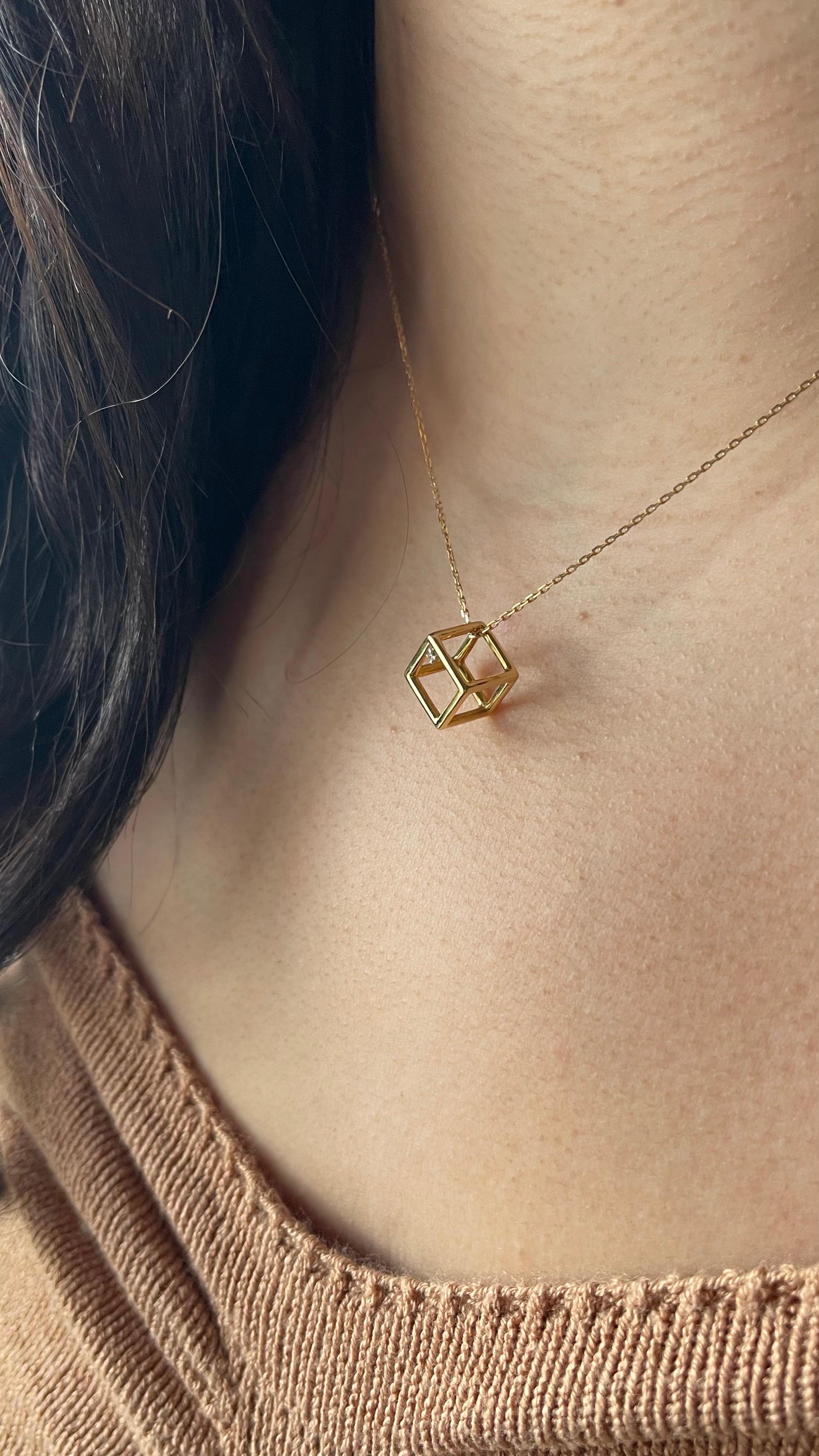 Questa elegante collana presenta un ciondolo a forma di cubo tridimensionale realizzato a mano in oro giallo 18 carati. Minimalista ma accattivante, il cubo con cornice aperta è progettato con linee pulite e un'estetica elegante e moderna.