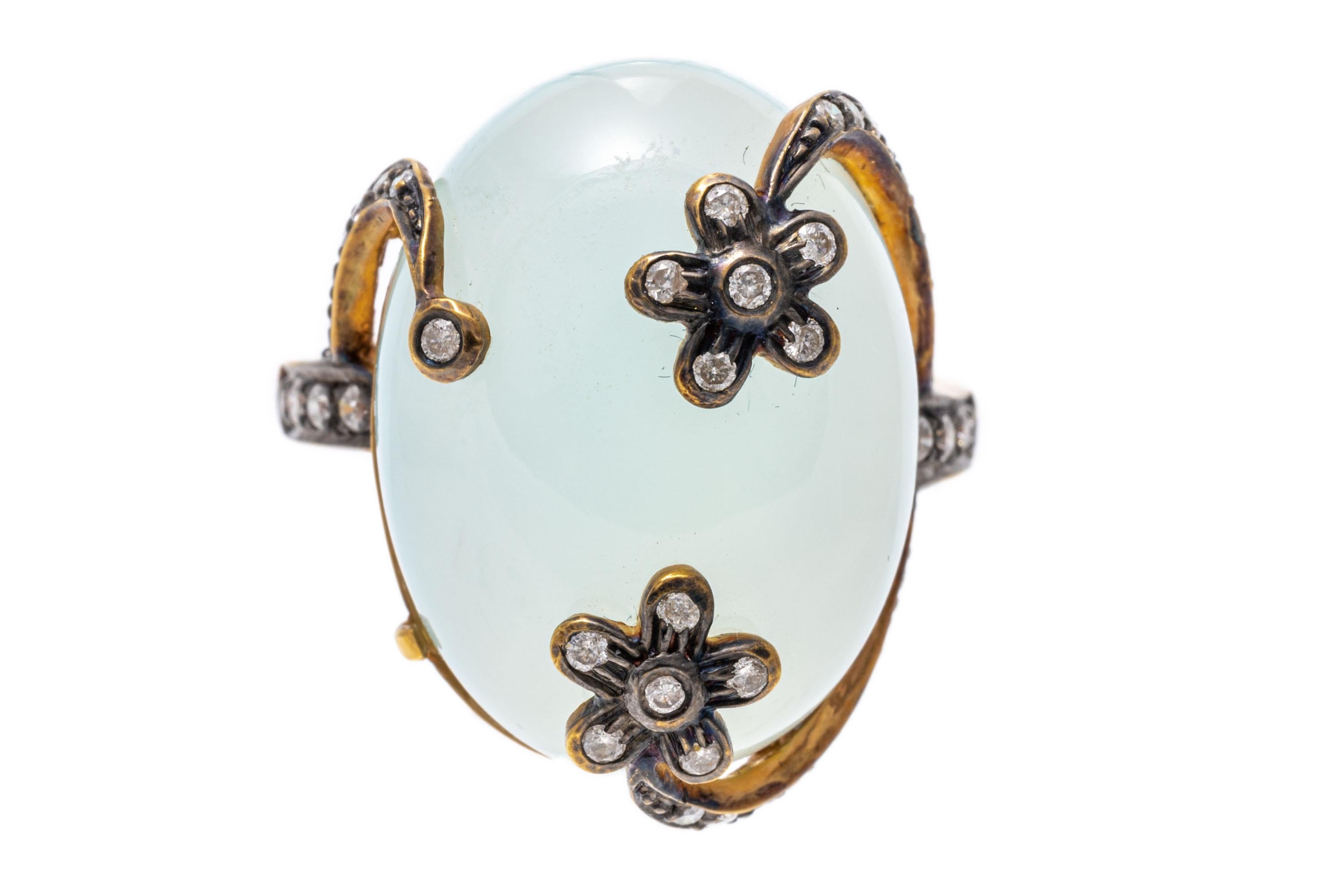 18k yellow gold ring. This pretty yellow gold contemporary ring has an oval, green- blue chalcedony cabachon center, set and flanked by round faceted cut diamonds set into flower motif prongs, and the shoulders, approximately 0.20 TCW, blackened