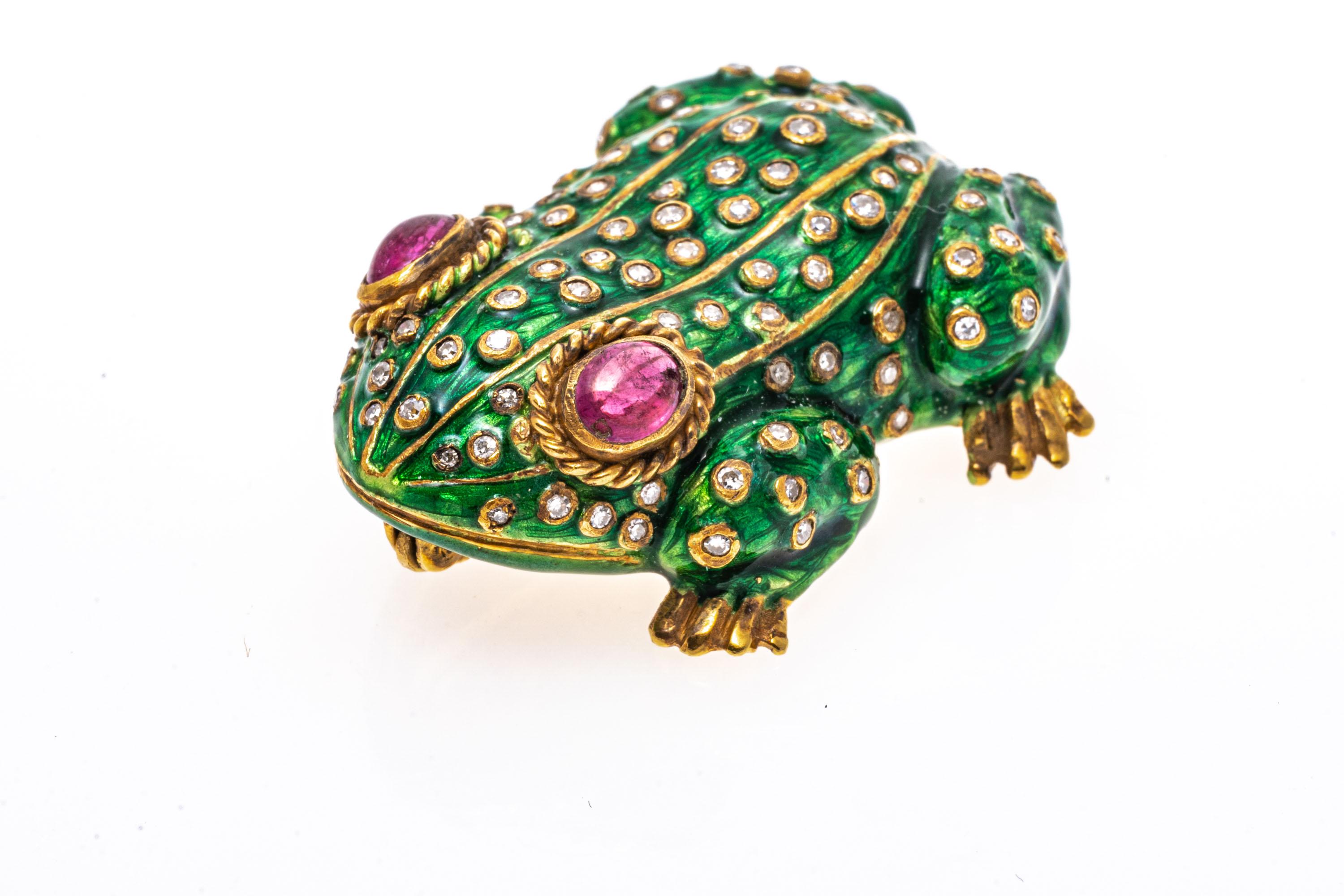 18k yellow gold brooch. This charming brooch is a figural frog, with a green enamel body decorated with scattered bezel set, round faceted diamonds, approximately 0.38 TCW. Finishing the brooch are two large pinkish red oval, bezel set synthetic