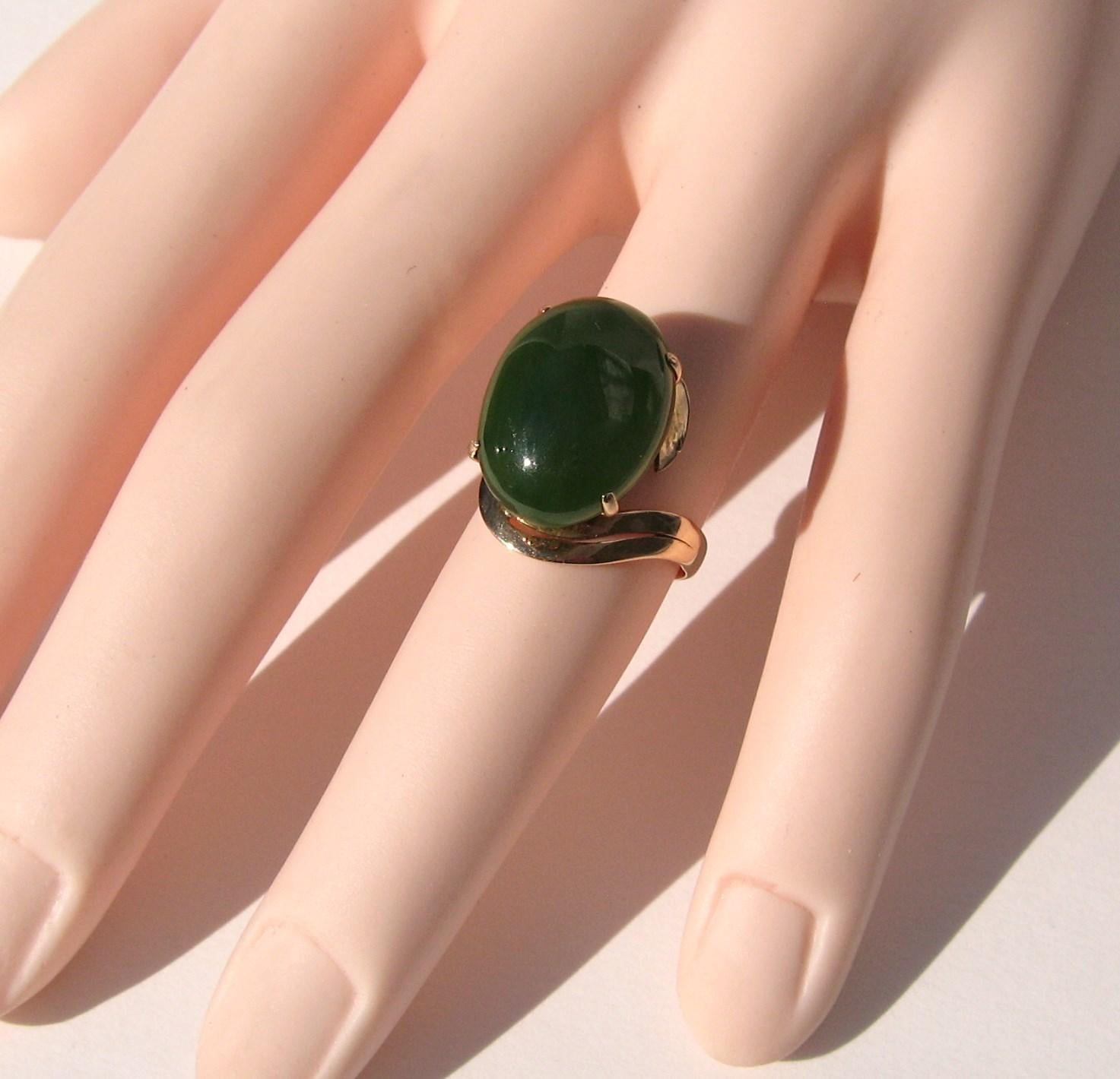 Ravissante parure de jade verte ovale du milieu du siècle en or 18 carats. La tige est en forme de tourbillon et le jade est placé en haut de la tige. Mesurant 0,69 x 0,51 pouces. Il est monté de 0,45 pouce. La bague est une taille 5.5. Elle peut