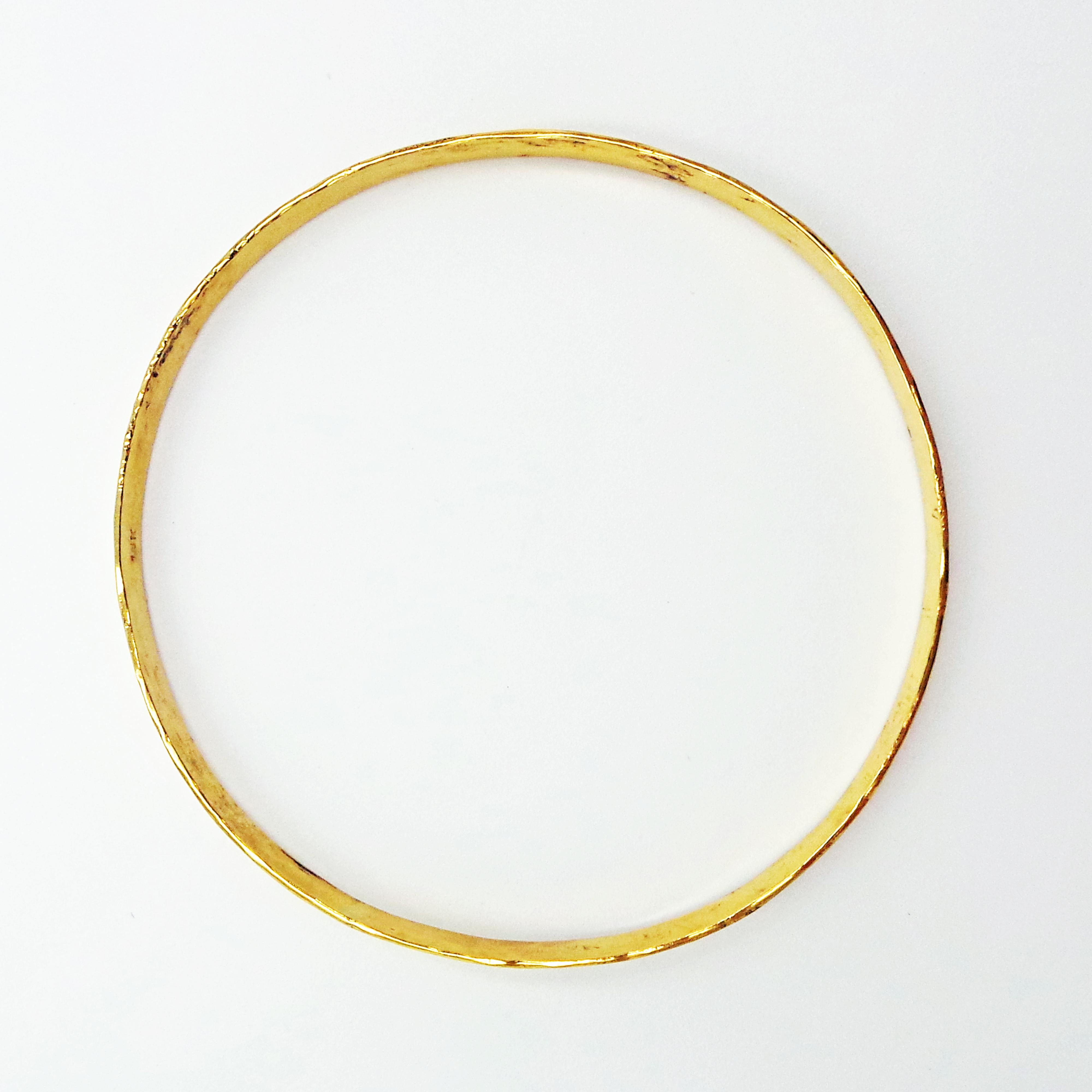 Solid 18k yellow gold bangle is hand-forged and finished with a hammered, rustic texture. Bracelet is 2.5