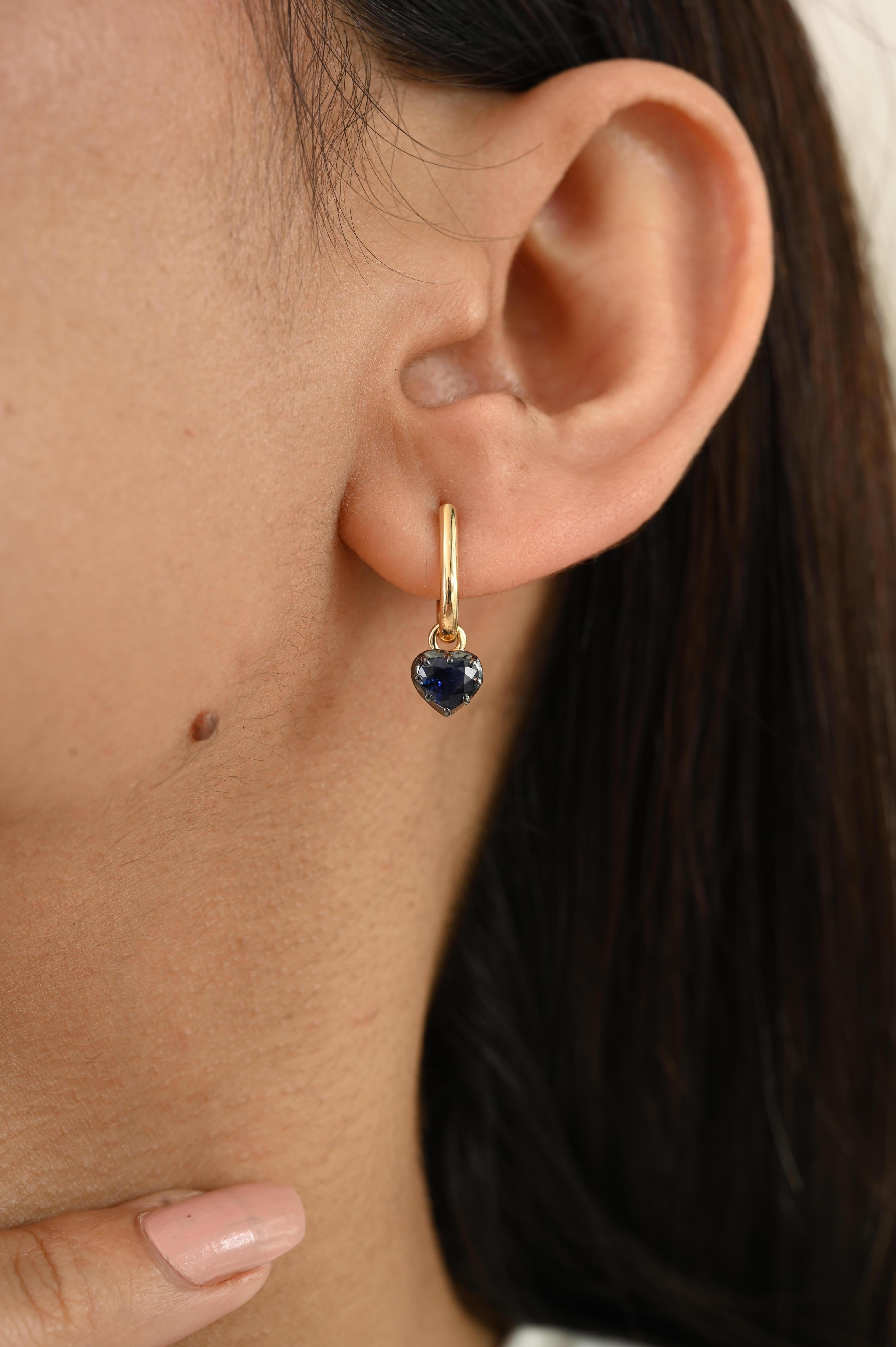 Ces boucles d'oreilles exquises sont réalisées en or jaune 18 carats et en or jaune noirci et mettent en valeur deux saphirs bleus en forme de cœur d'un poids total de 0,93 carats. Chaque saphir de 4 x 5 mm rayonne d'une riche teinte bleue veloutée