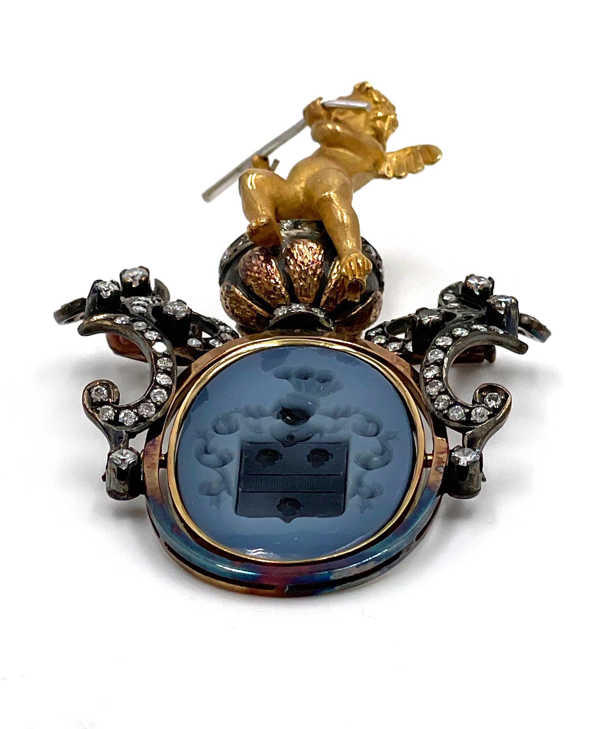 Spilla/pendente d'epoca in oro giallo 18 carati, con incisione e diamanti.  La spilla presenta un grande cherubino a figura intera nella parte superiore, seduto su un'urna con diamanti incastonati.  La cornice ovale sottostante è girevole ed è