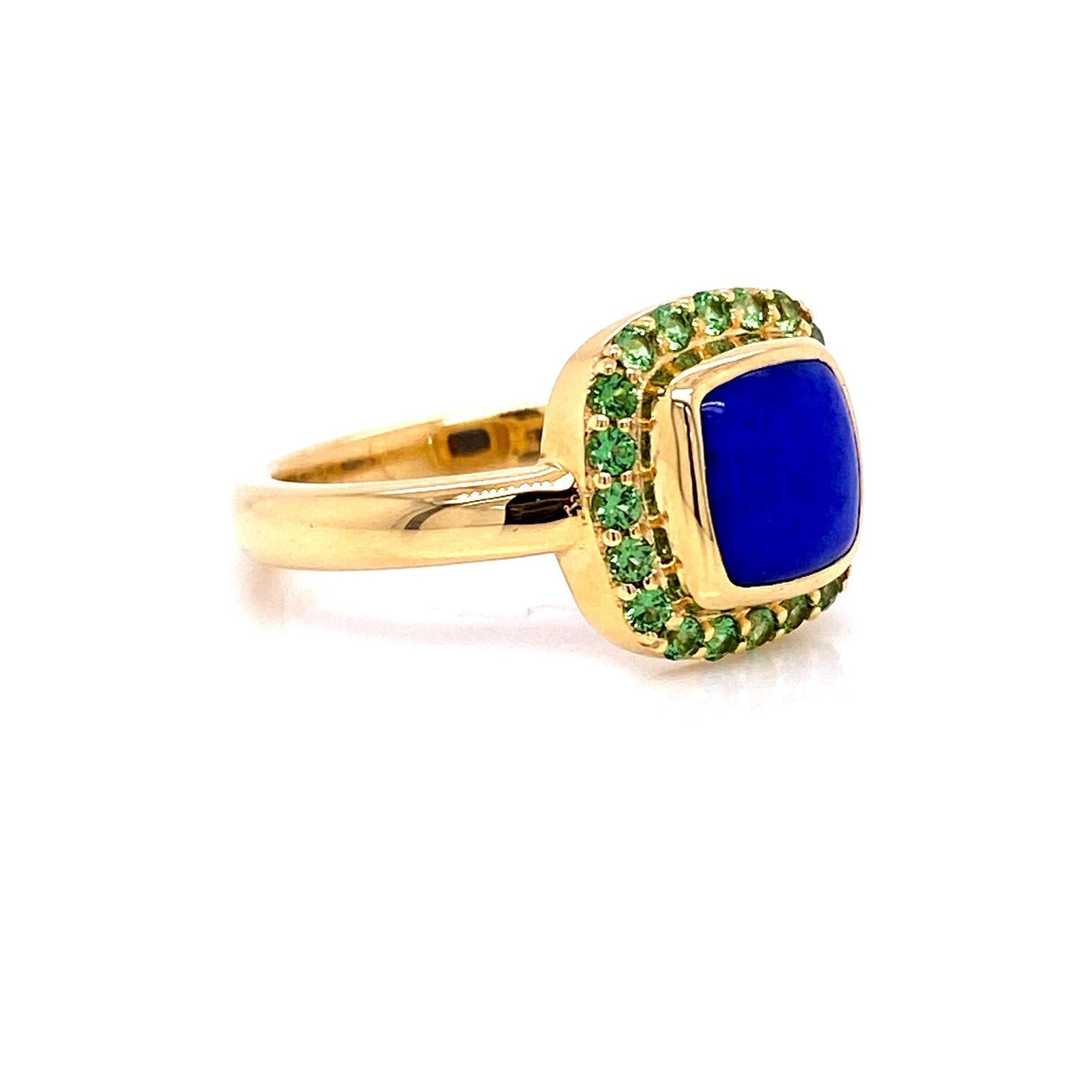 An 18k yellow gold ring set with one 7.39mm x 7.44mm Lapis Lazuli cushion shaped cabochon, and twenty 1.5mm Tsavorite garnets, .30 total carat weight. Ring size 6.75. This ring was made and designed by llyn strong.