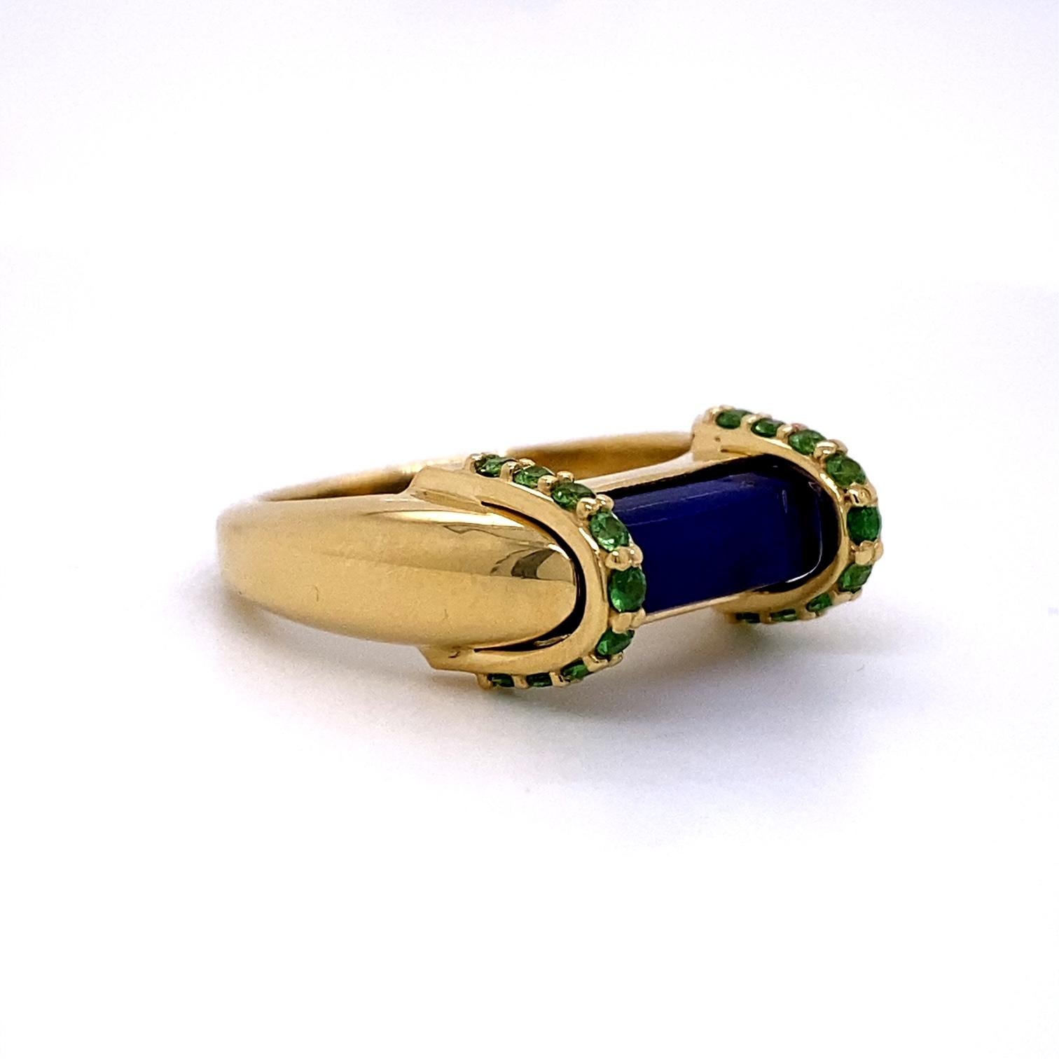 An 18 yellow gold ring set with a 2.68 carat lapis lazuli and two straps of 1.6mm tsavorite garnets for a total of .36 carats. Ring size 7. This ring was made and designed by llyn strong.